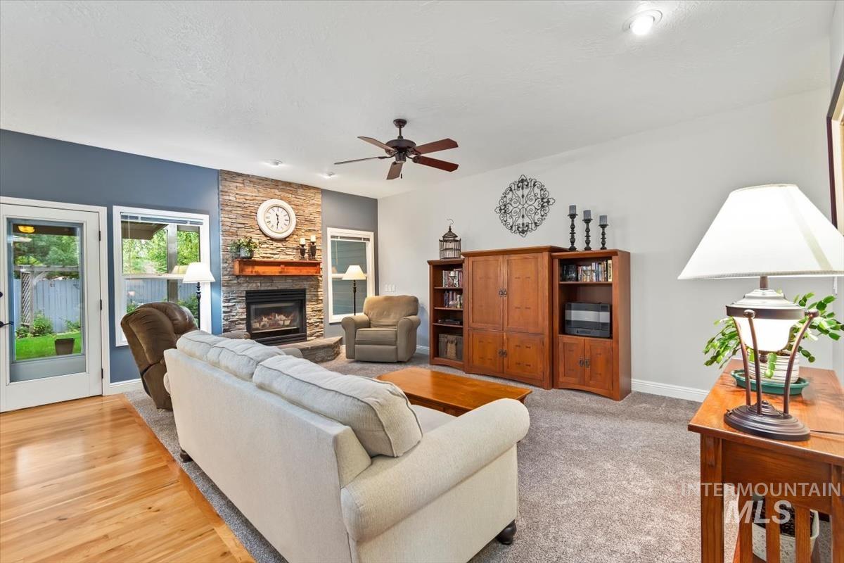 Living room with a fireplace, a ceiling fan, and light wood-type flooring