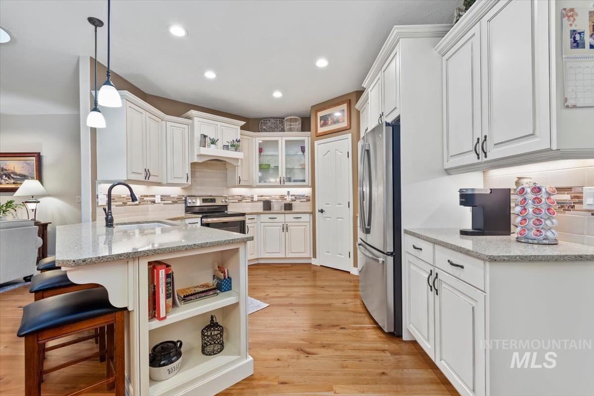 Kitchen with backsplash, glass insert cabinets, a kitchen bar, open shelves, and white cabinets