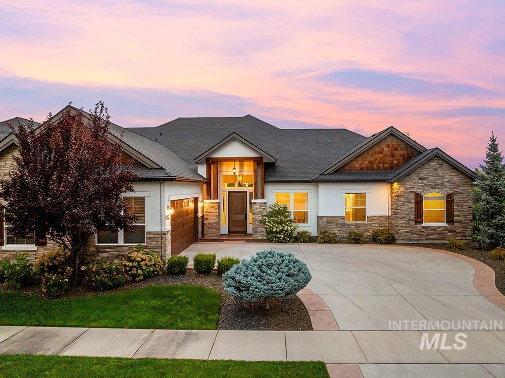 Craftsman-style home with stone siding, driveway, an attached garage, and stucco siding
