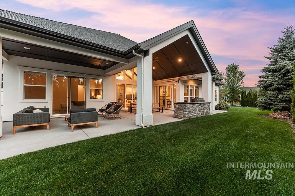Rear view of property featuring a yard, a patio, and roof with shingles