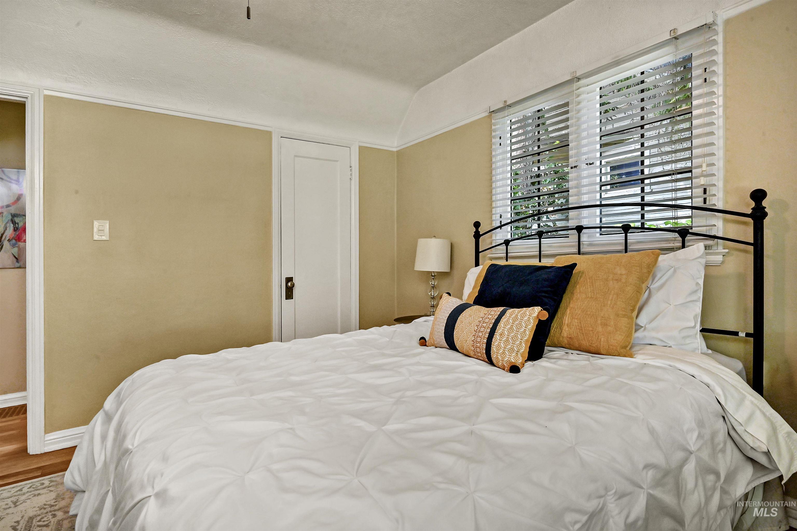 Bright bedroom with hardwood floors, coved ceiling & large windows that fill the space with soft natural light.