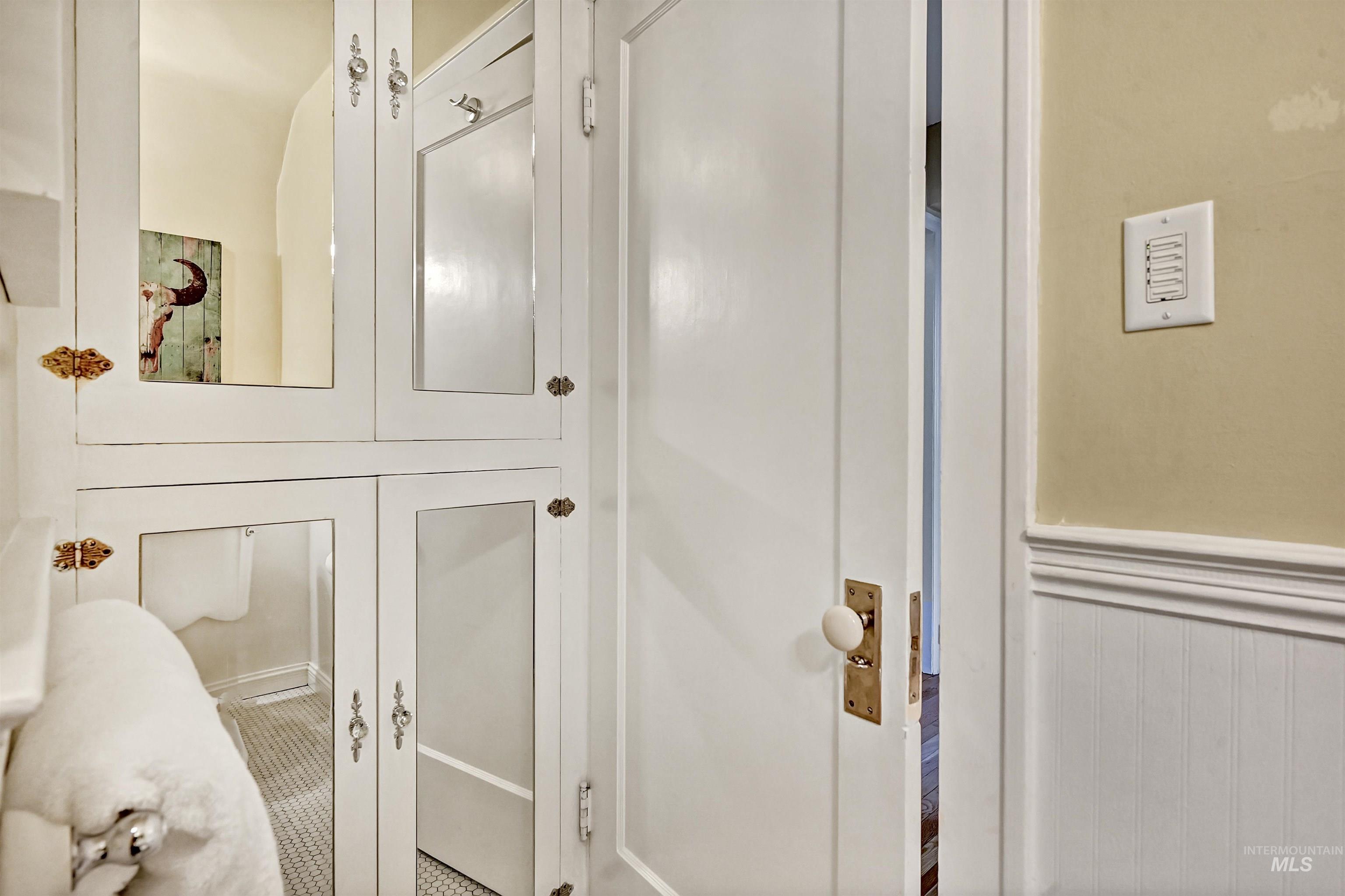 Built-in cabinetry with mirrored doors & vintage hardware adds charm & practical storage to the bathroom.