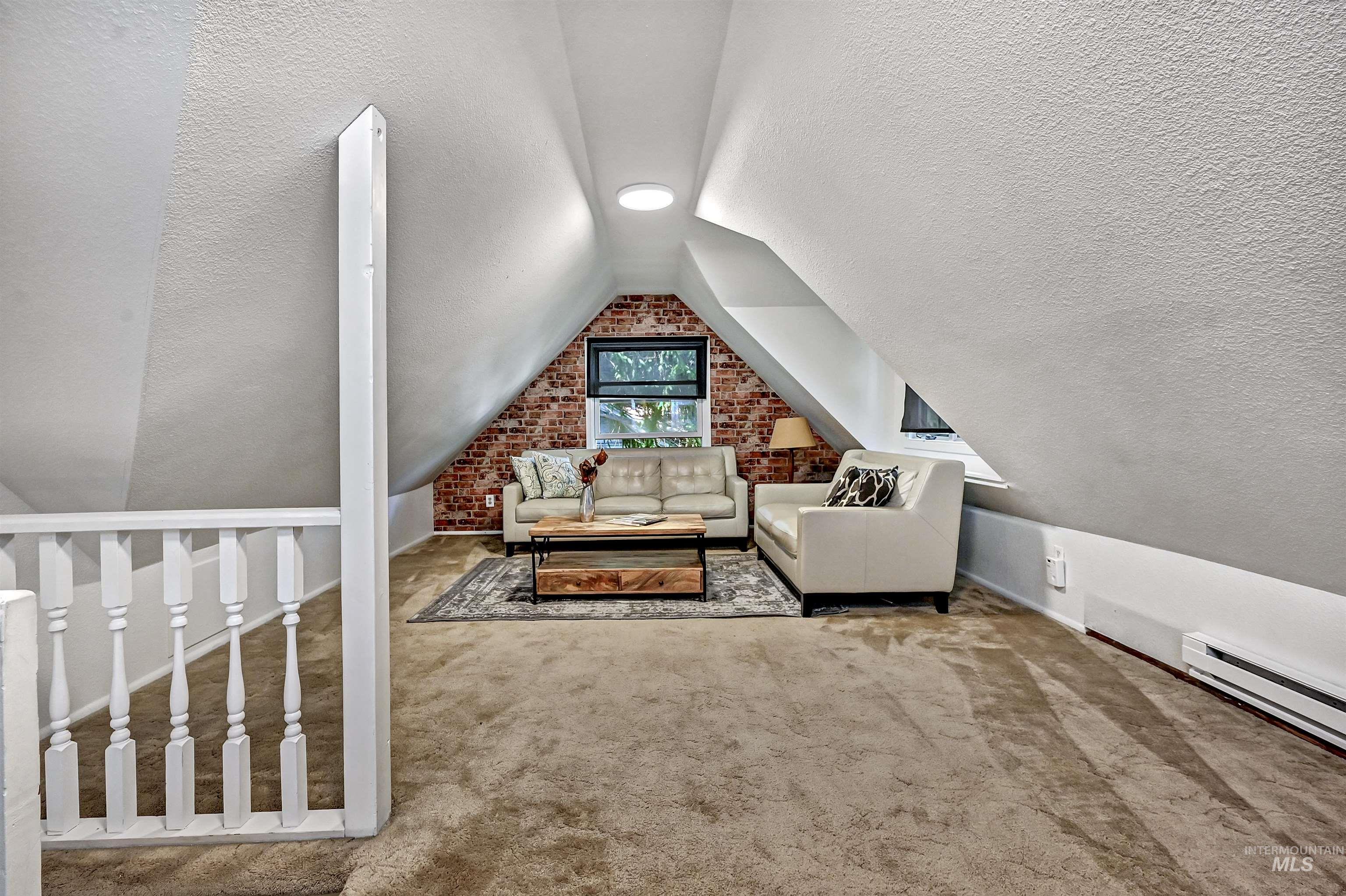 Versatile upstairs space with angled ceilings & a faux-brick accent wall—ideal for a family room, media room, or guest retreat.