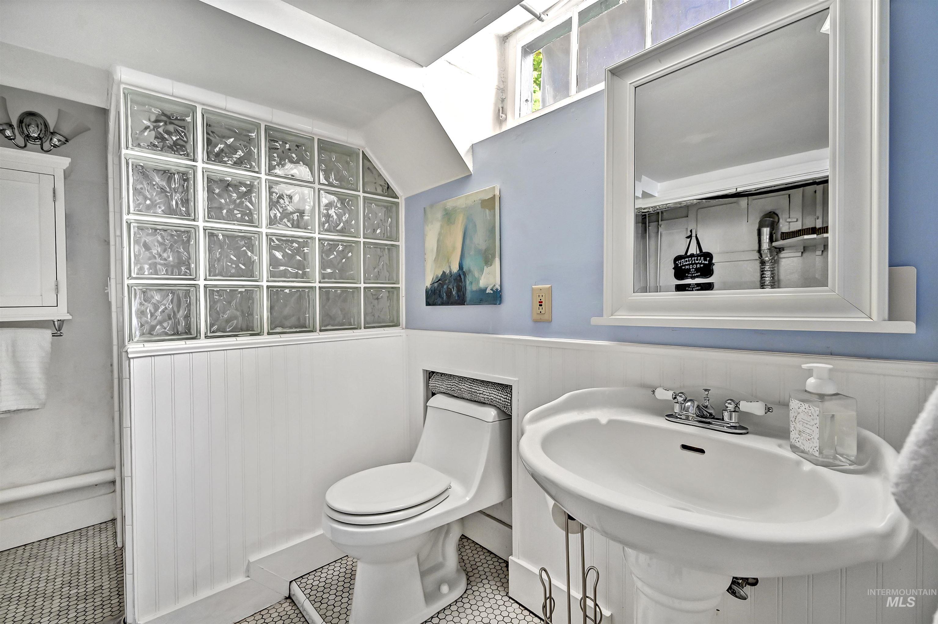 Charming lower-level bathroom with beadboard wainscoting, pedestal sink & glass block detail that adds style & privacy.