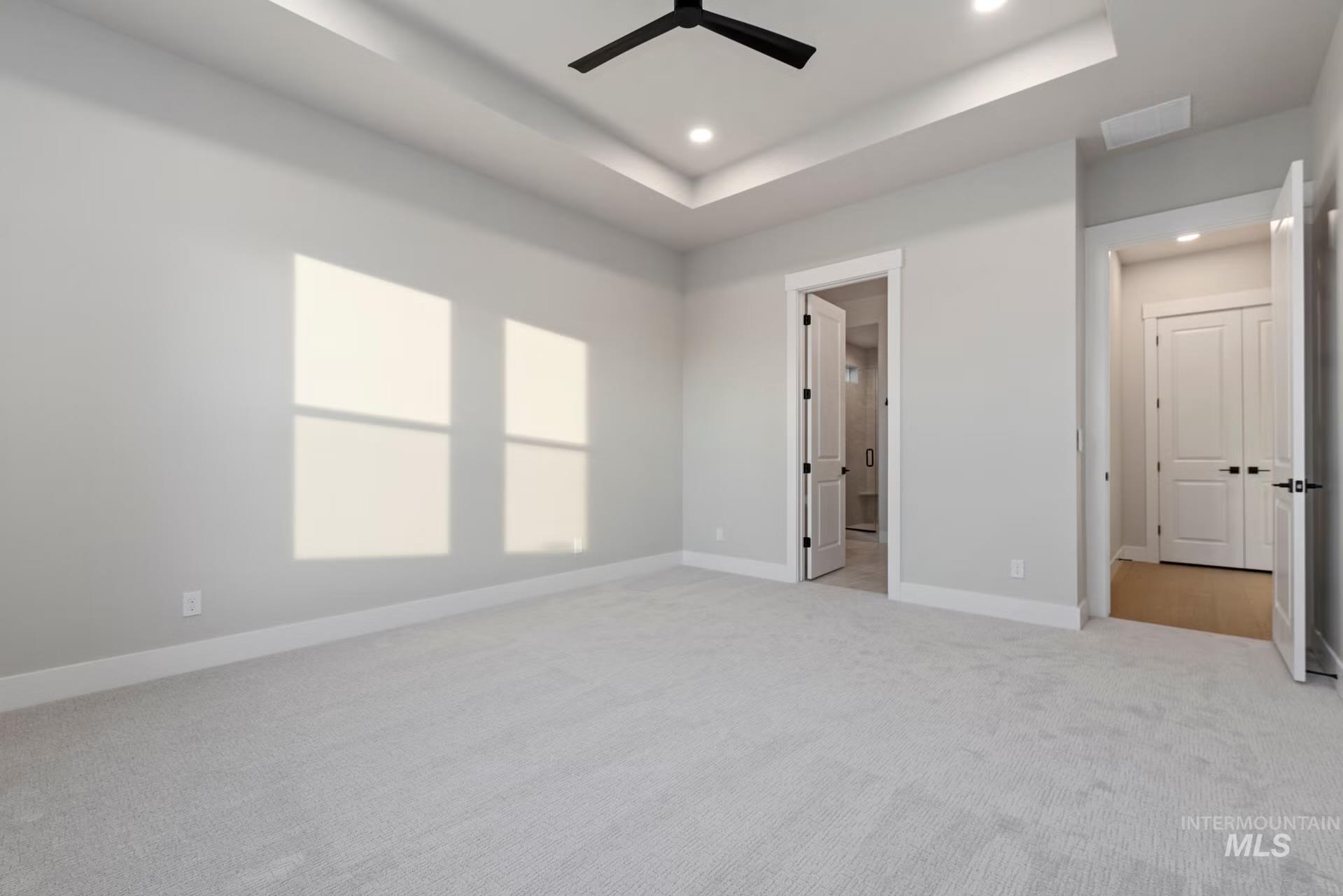 Unfurnished bedroom featuring a tray ceiling, light carpet, ceiling fan, and recessed lighting