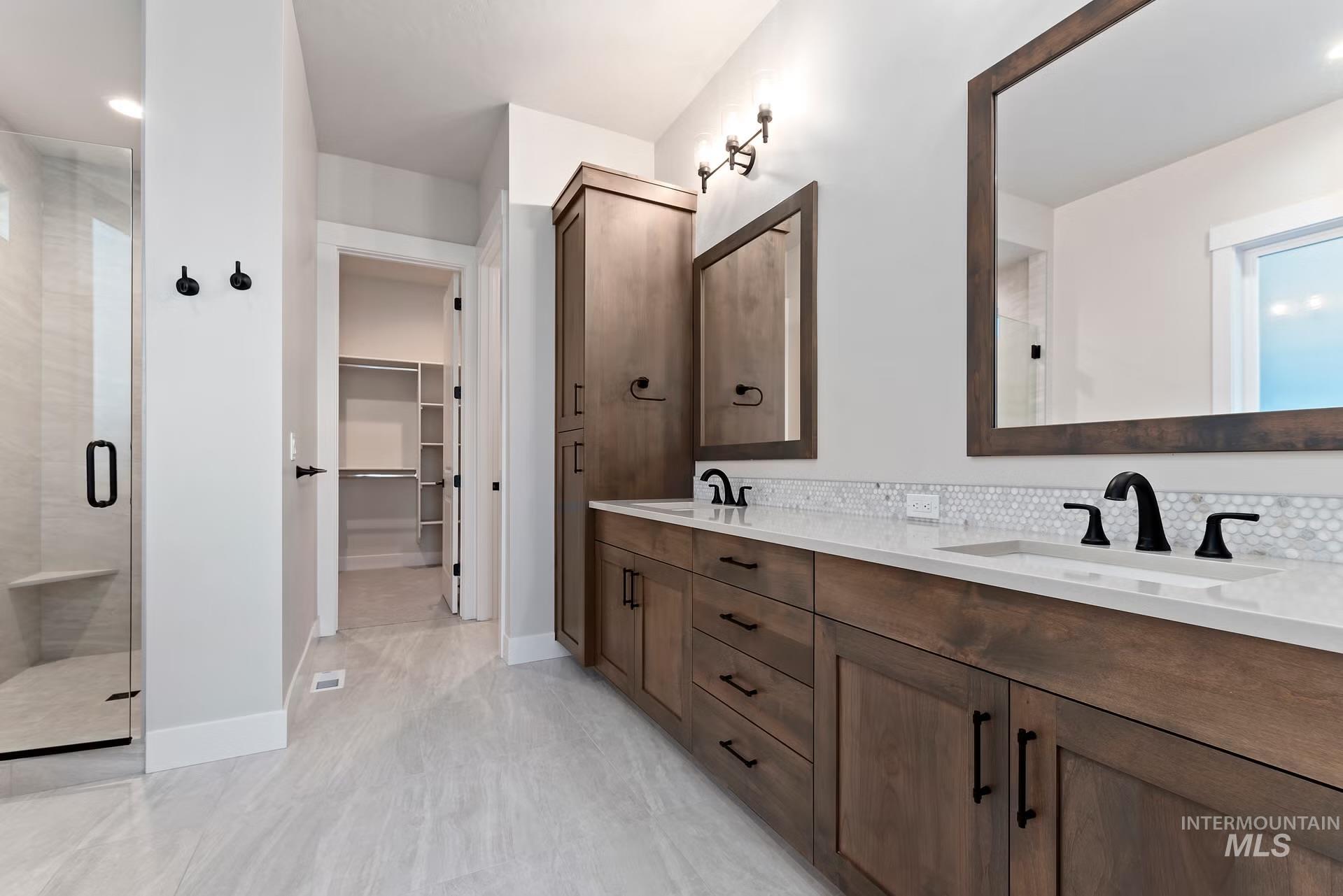 Bathroom with double vanity, backsplash, a spacious closet, and an enclosed shower