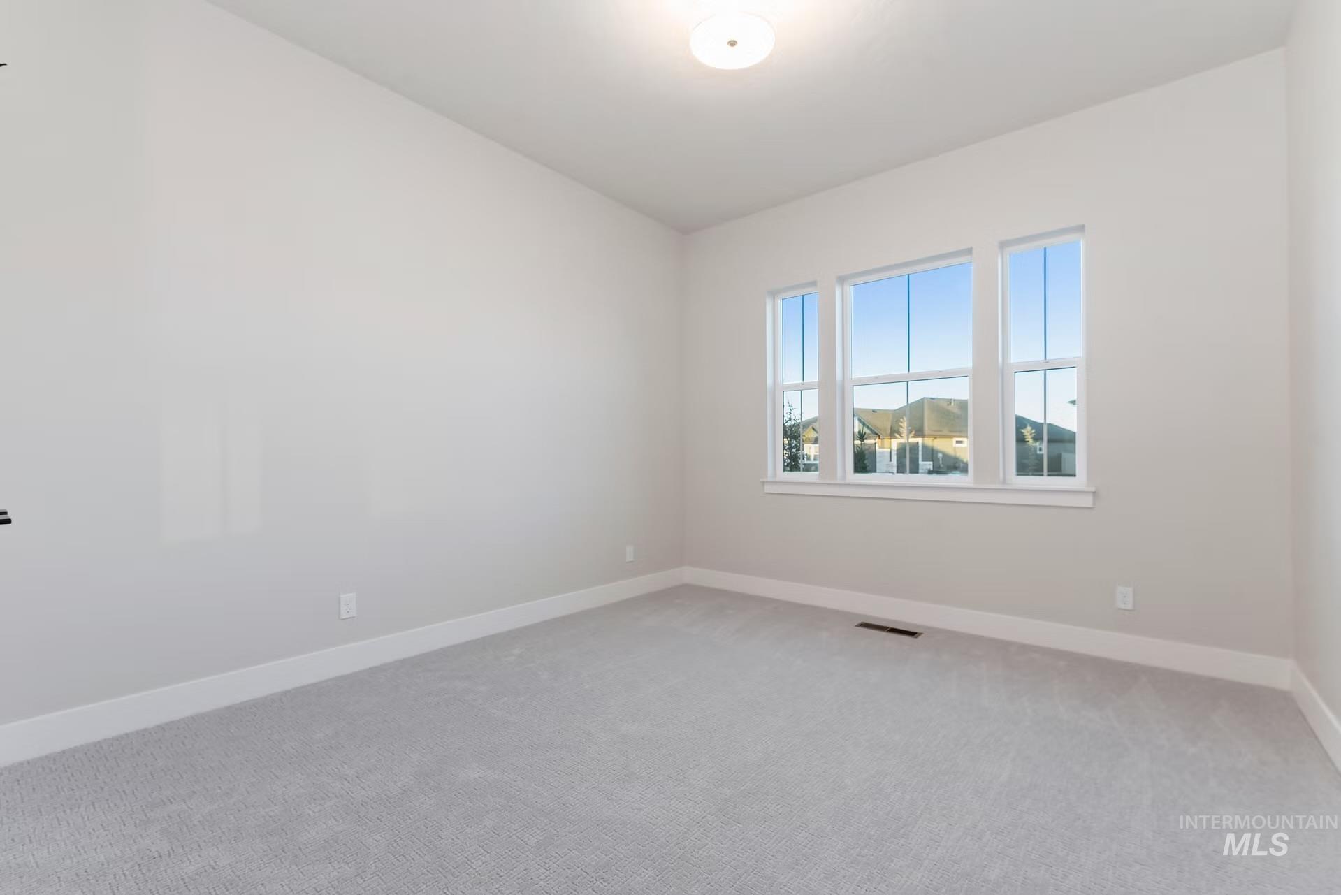 Carpeted spare room featuring baseboards