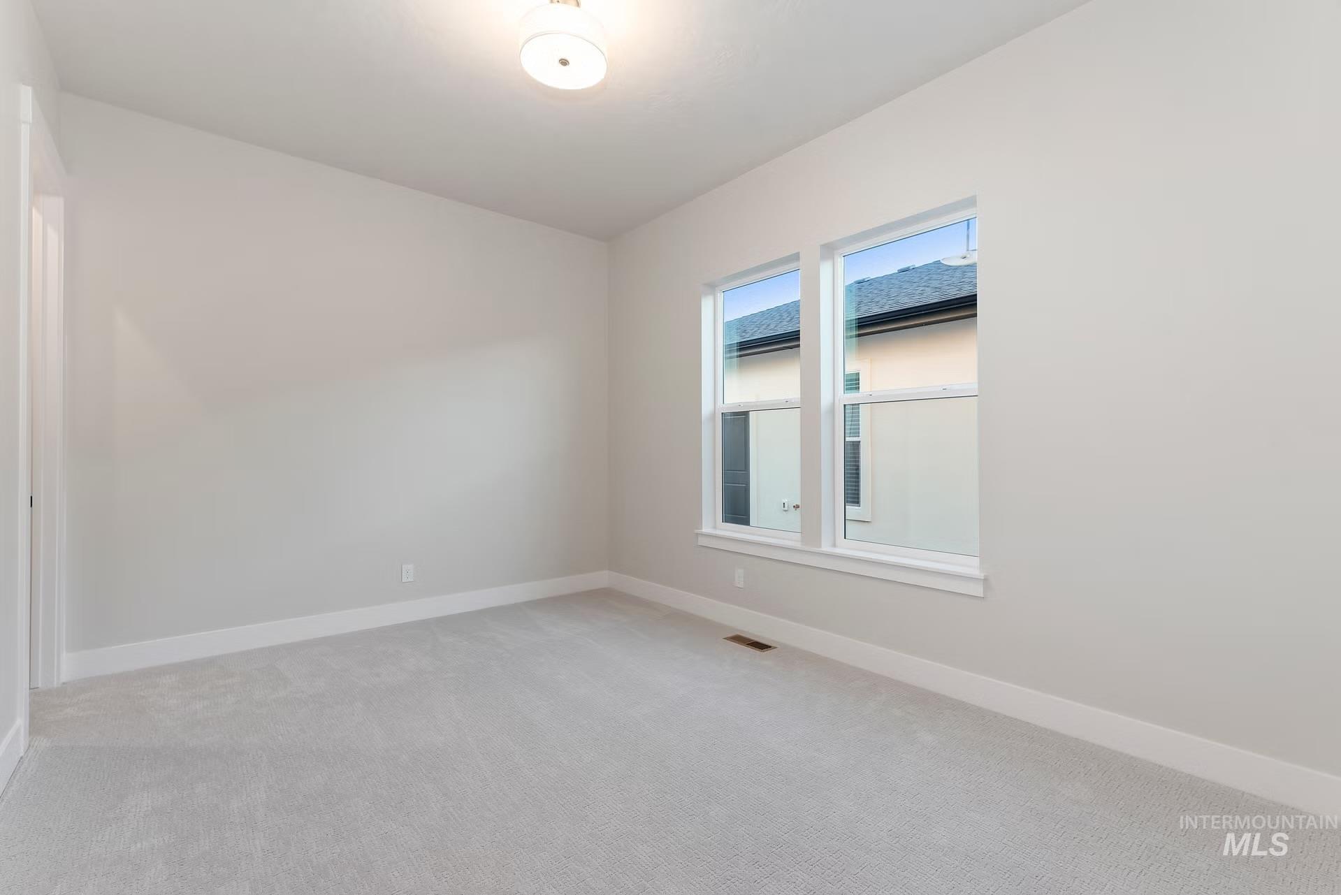 Spare room with light carpet and baseboards