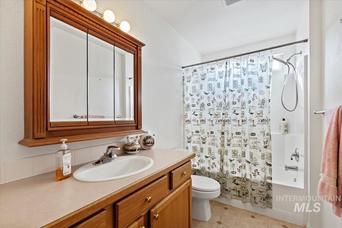 Bathroom featuring vanity, shower / tub combo, and light tile