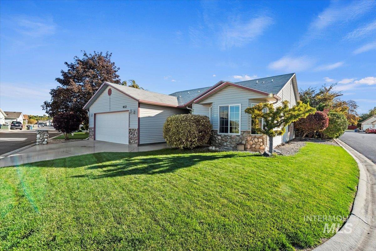 View of front of house with stone and siding, driveway, a garage, and large front lawn