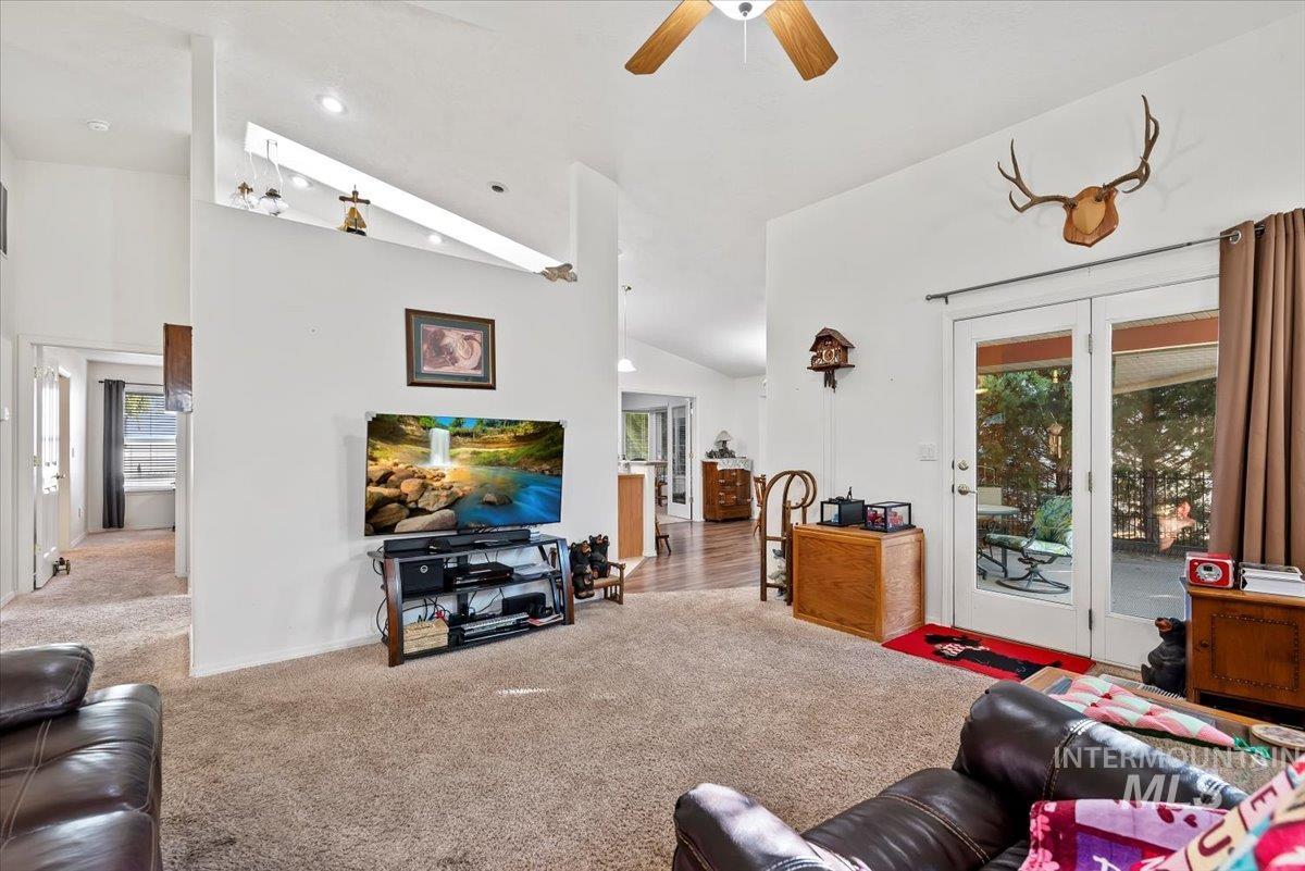 Carpeted living area with high vaulted ceiling, ceiling fan, and recessed lighting