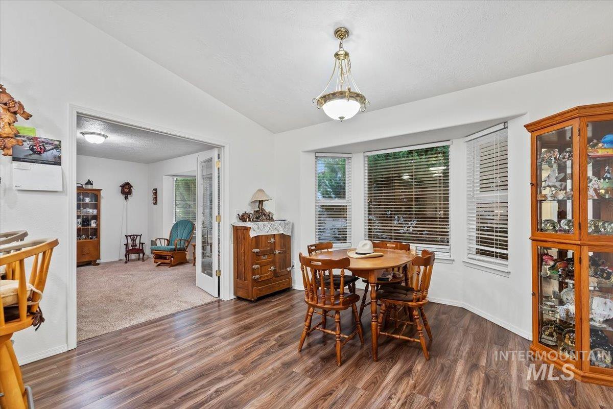 Dining area featuring dark wood-style floors and vaulted ceiling