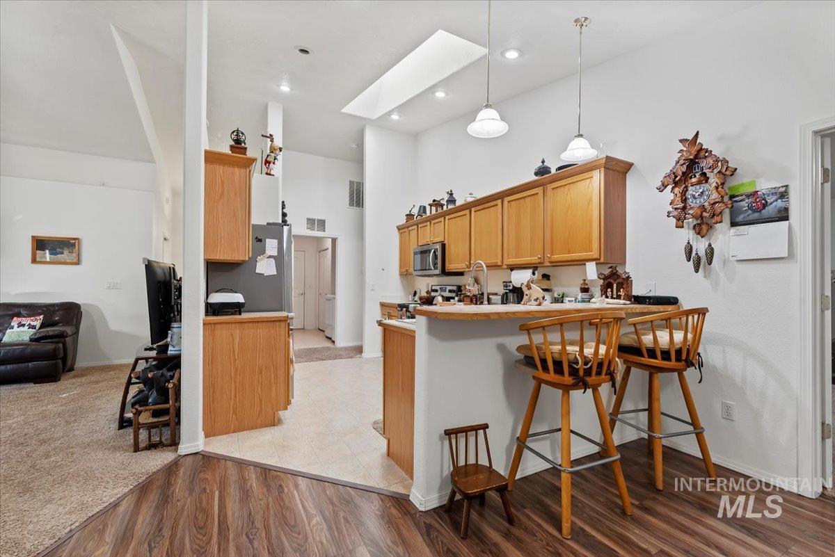 Kitchen featuring a skylight, a kitchen bar, wood-style floors