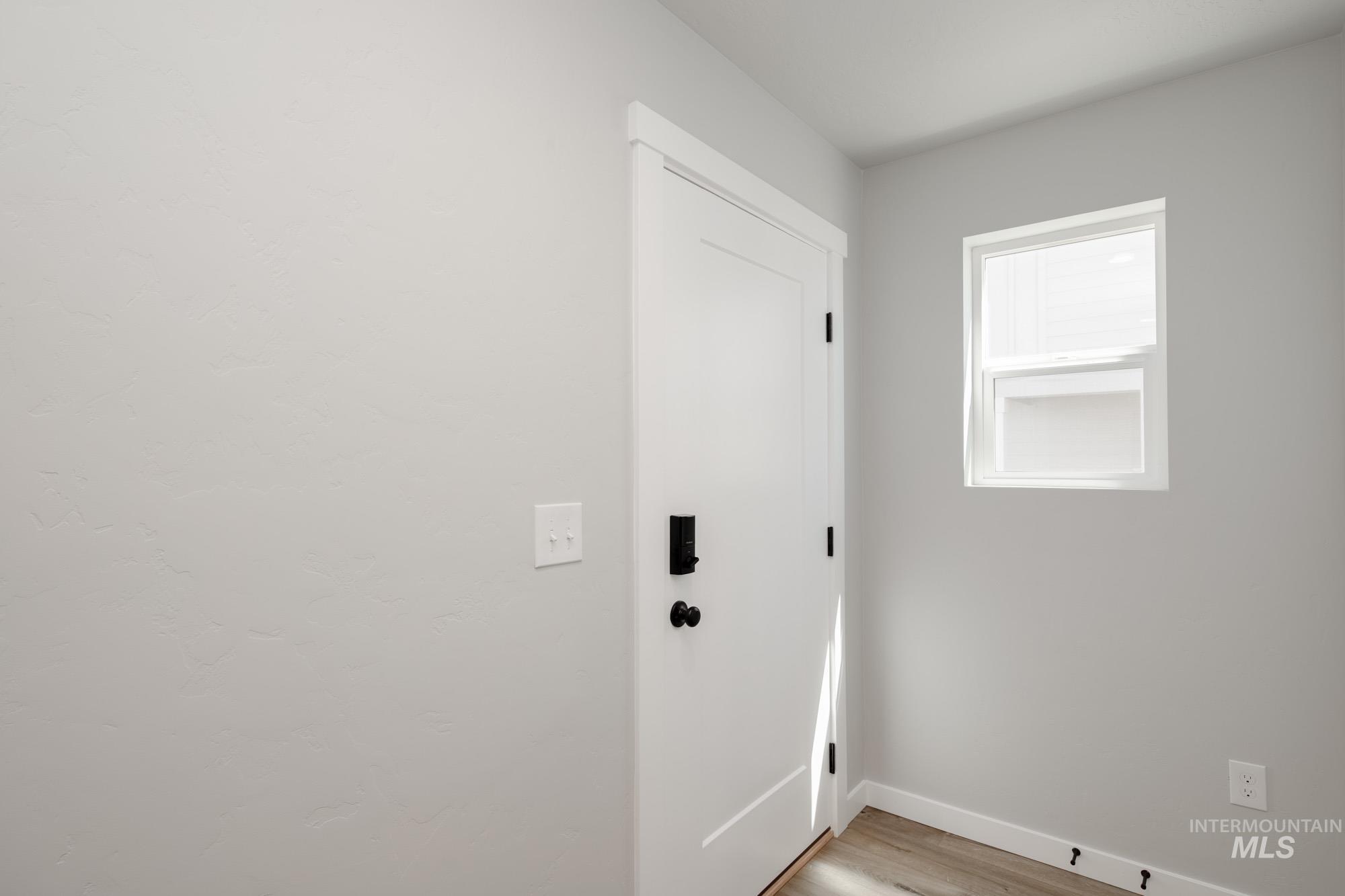 Doorway with wood finished floors and baseboards
