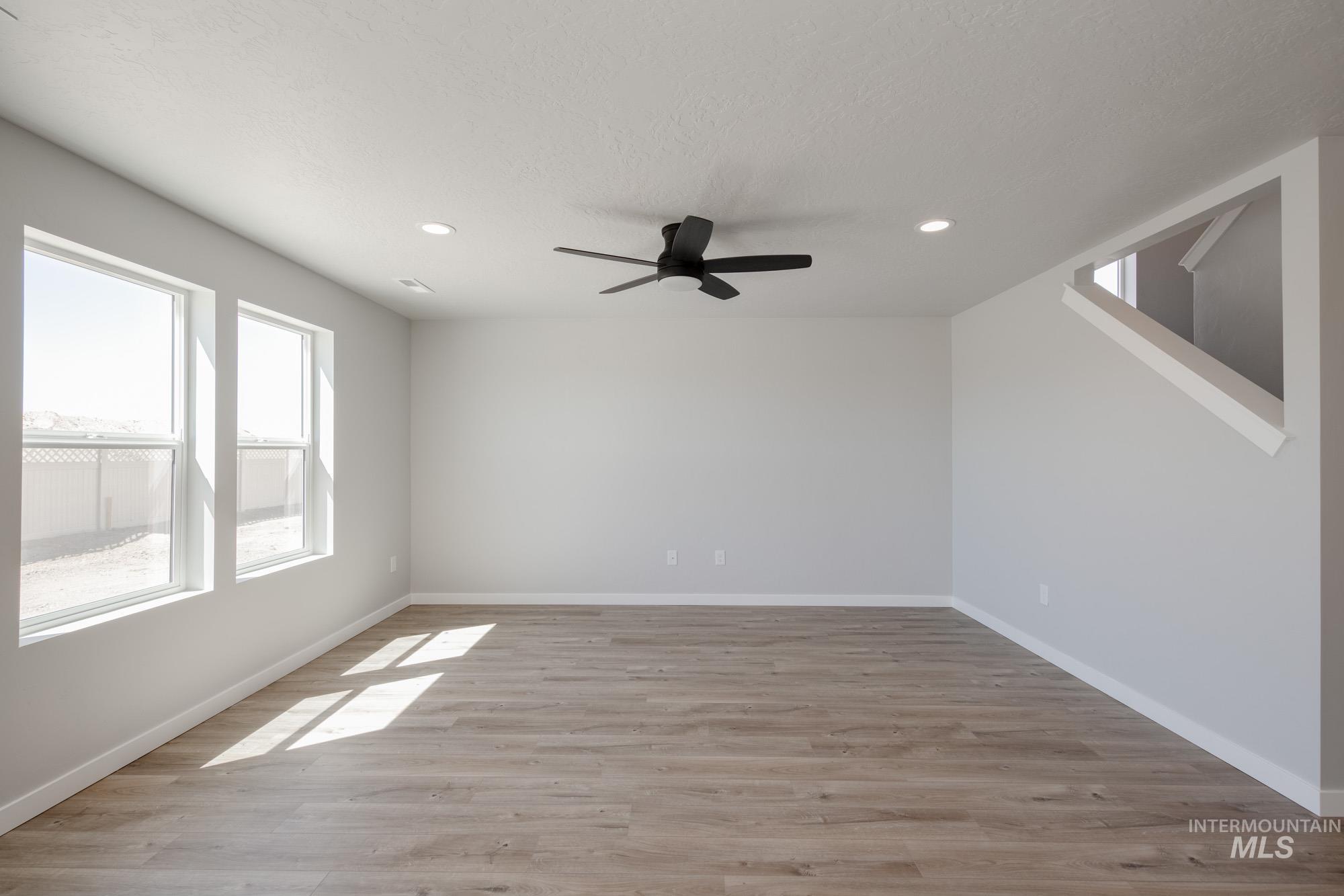 Empty room featuring light wood-style flooring, recessed lighting, ceiling fan, and a textured ceiling
