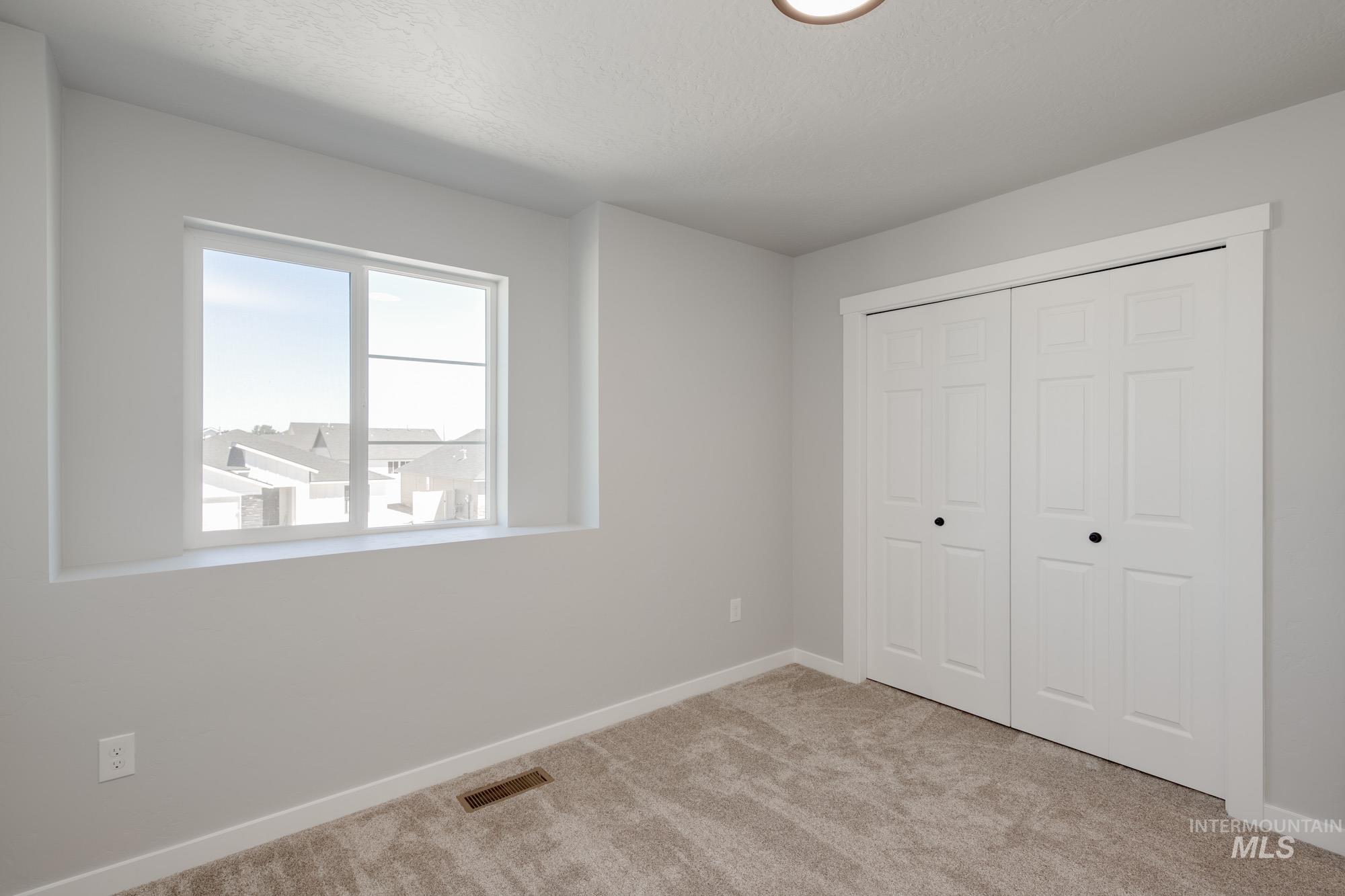 Unfurnished bedroom featuring light carpet and a closet
