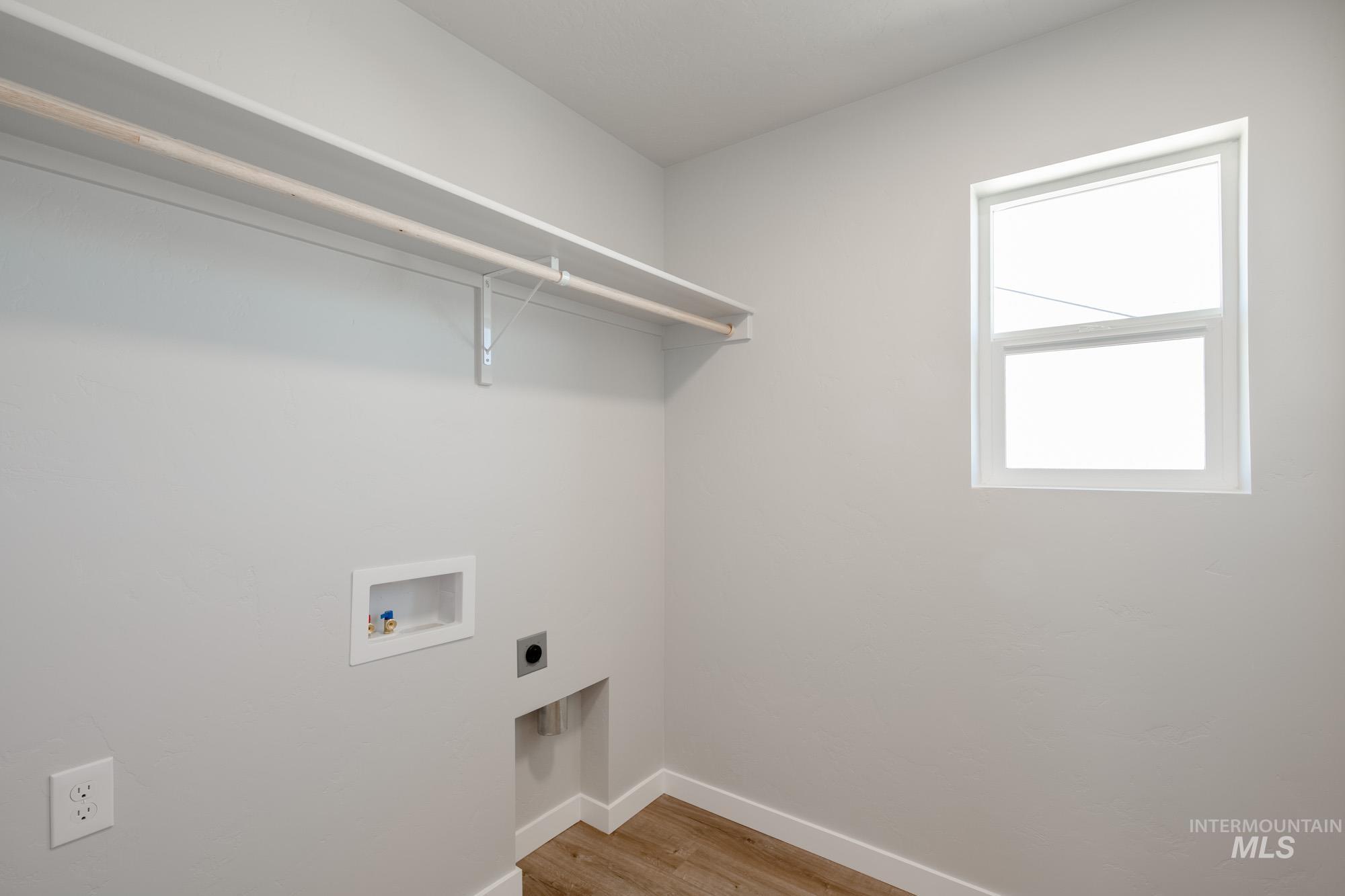 Laundry area with light wood-type flooring, hookup for a washing machine, and electric dryer hookup