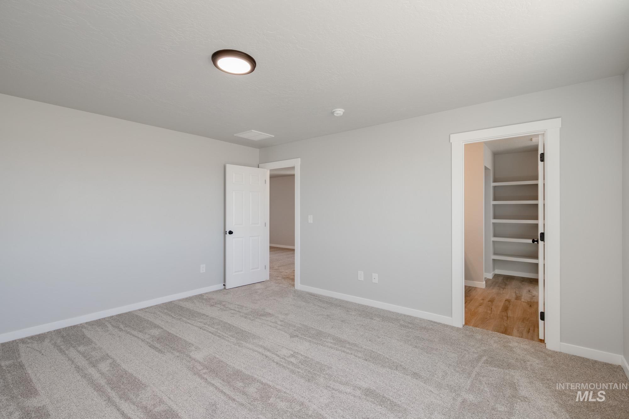 Unfurnished bedroom with light colored carpet and a walk in closet