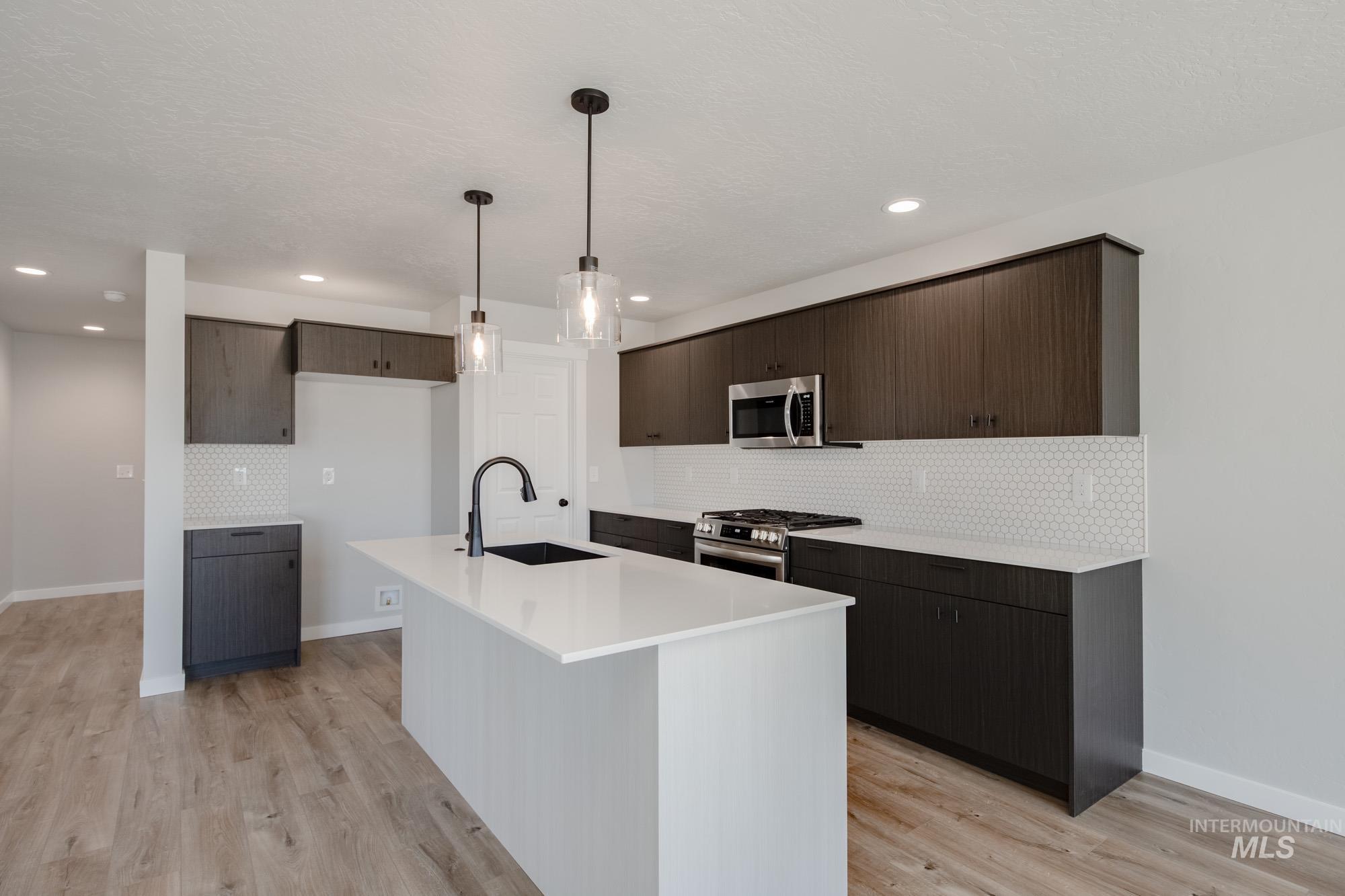 Kitchen with dark brown cabinets, modern cabinets, decorative backsplash, pendant lighting, and recessed lighting