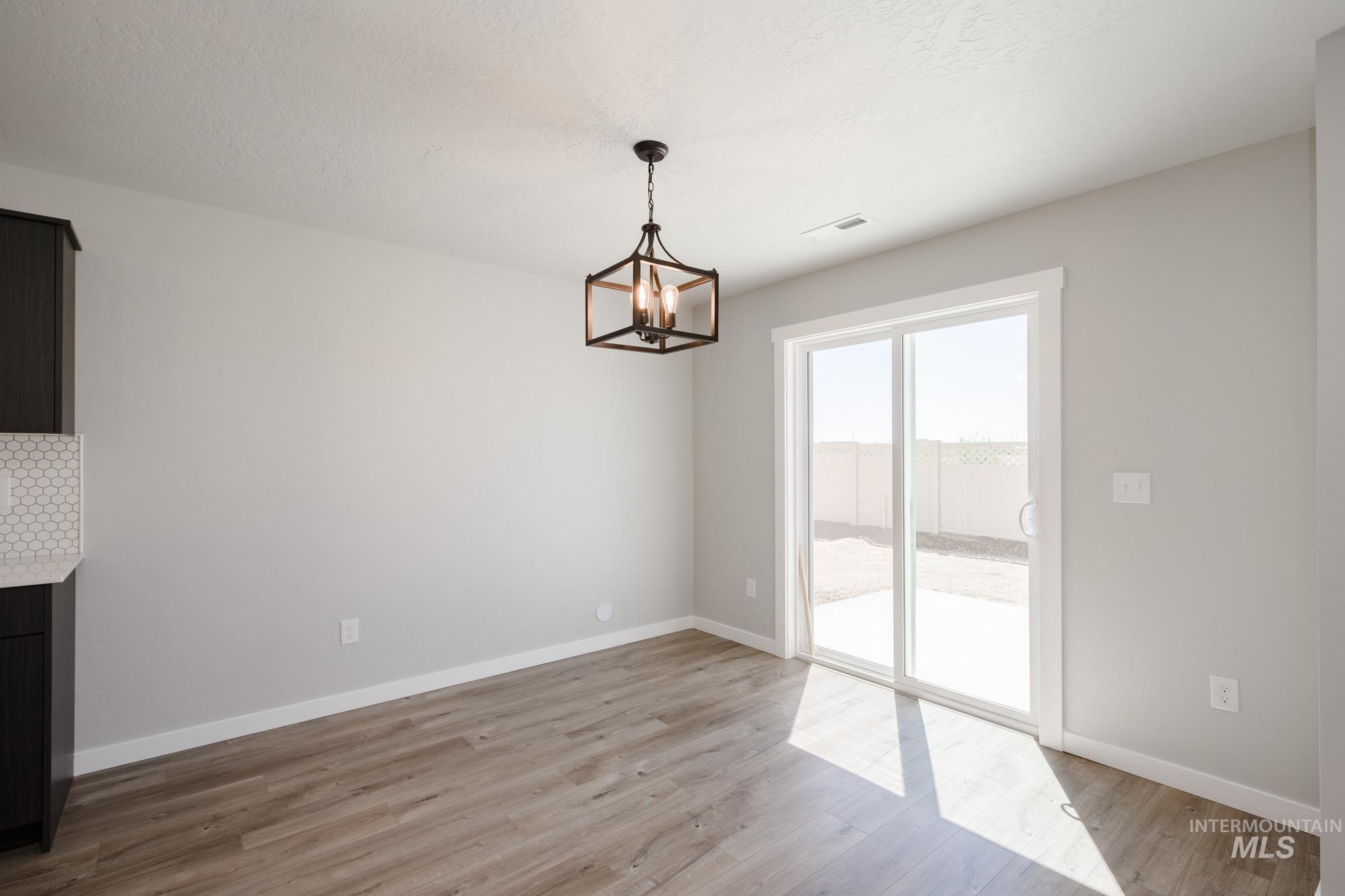 Unfurnished dining area with light wood-style flooring, a chandelier, and a textured ceiling