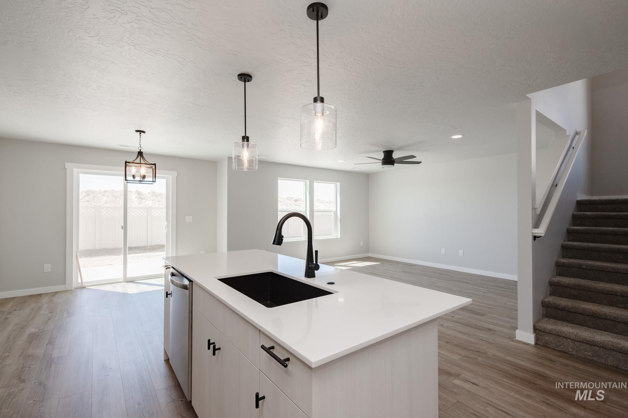 Kitchen with light wood-type flooring, hanging light fixtures, open floor plan, a textured ceiling, and a ceiling fan