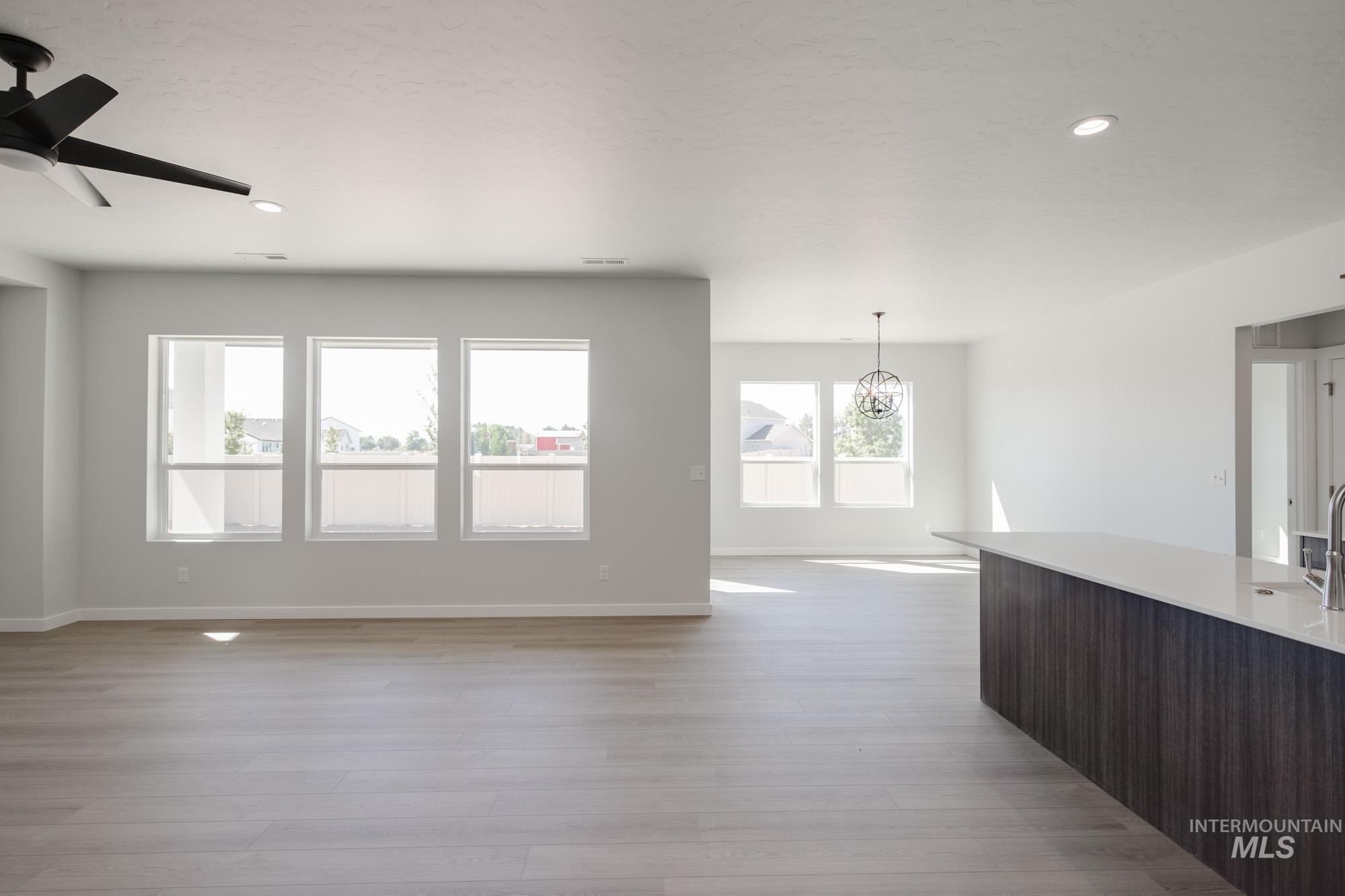 Unfurnished living room featuring recessed lighting, light wood-style flooring, a chandelier, and a ceiling fan