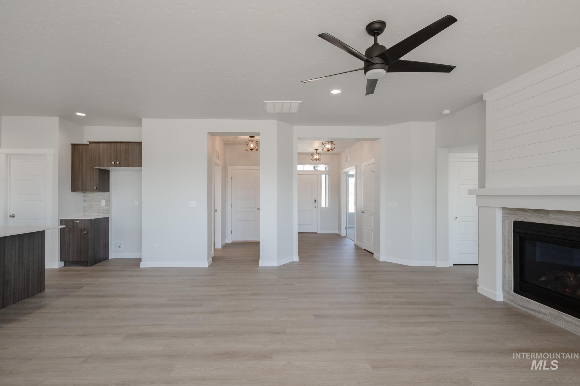 Unfurnished living room with light wood-style flooring, ceiling fan, a glass covered fireplace, and recessed lighting