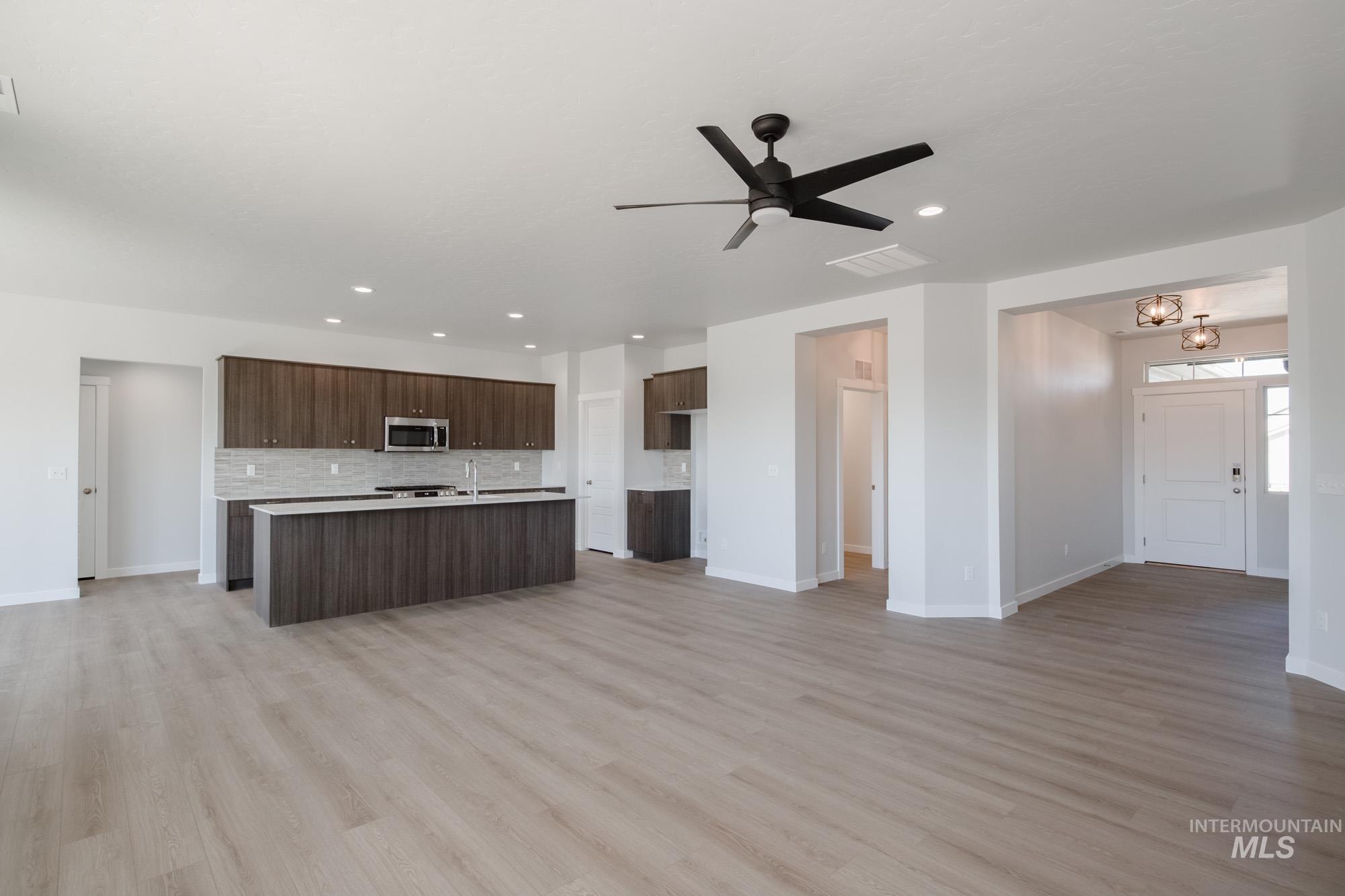Unfurnished living room with light wood-style flooring, a ceiling fan, and recessed lighting