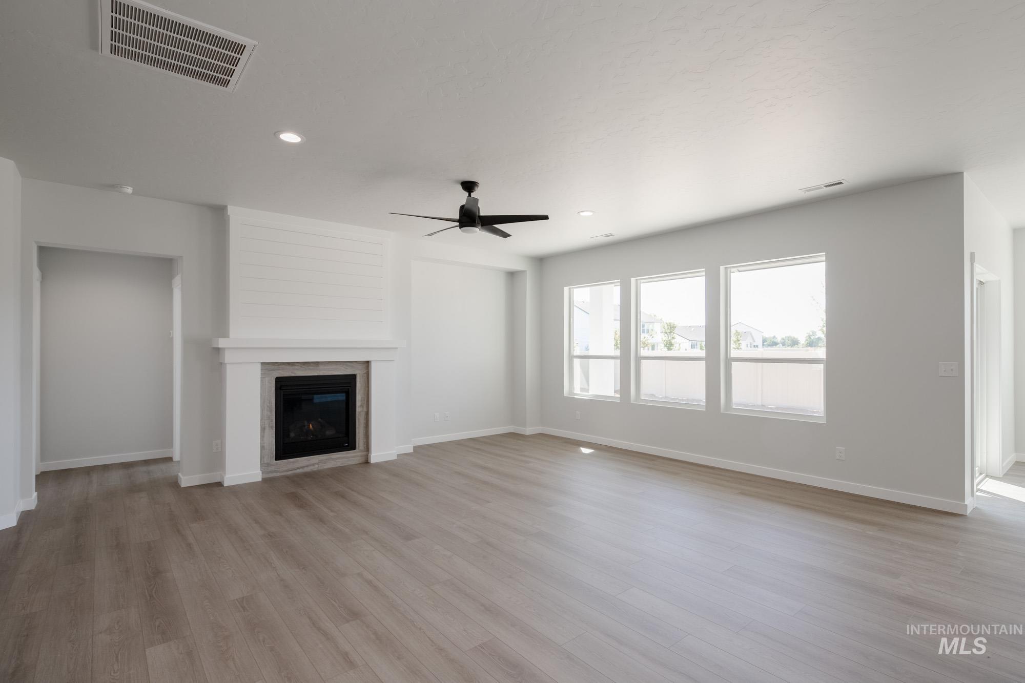 Unfurnished living room with light wood-type flooring, ceiling fan, a glass covered fireplace, and recessed lighting