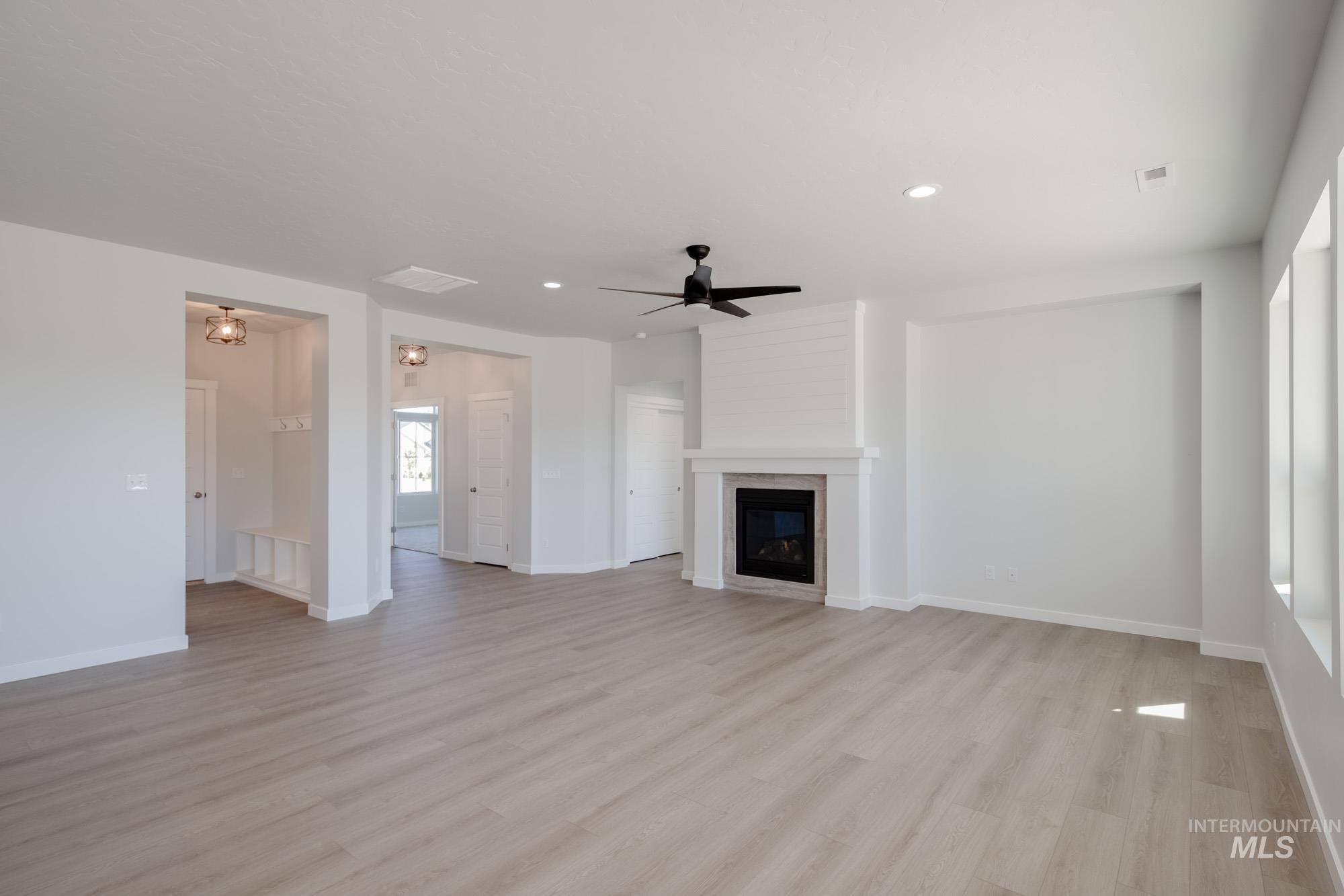 Unfurnished living room featuring light wood finished floors, a ceiling fan, recessed lighting, and a large fireplace