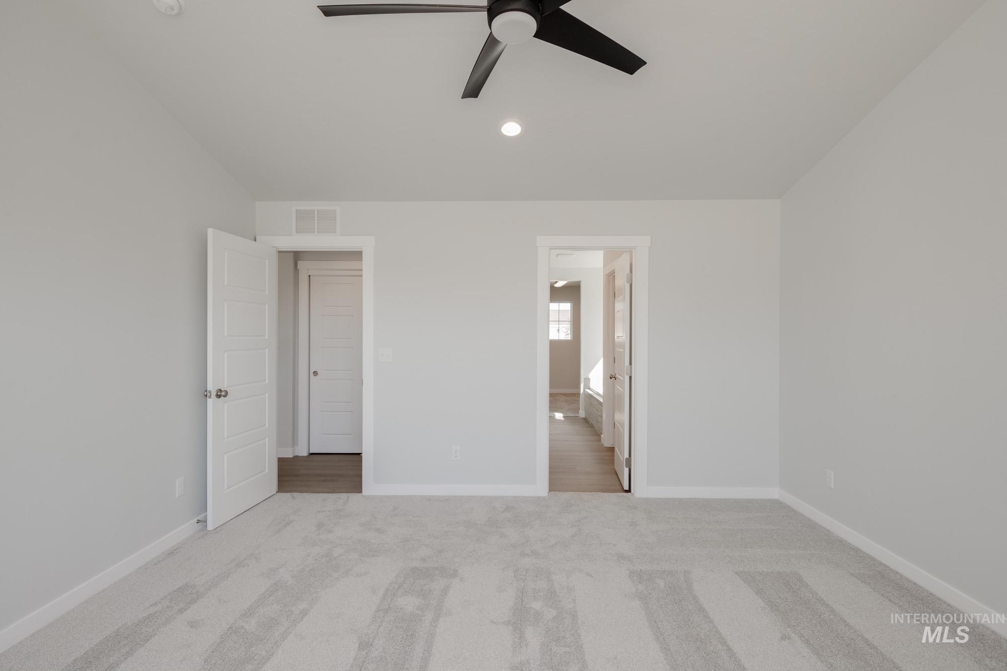Unfurnished bedroom with light carpet, ceiling fan, connected bathroom, lofted ceiling, and recessed lighting