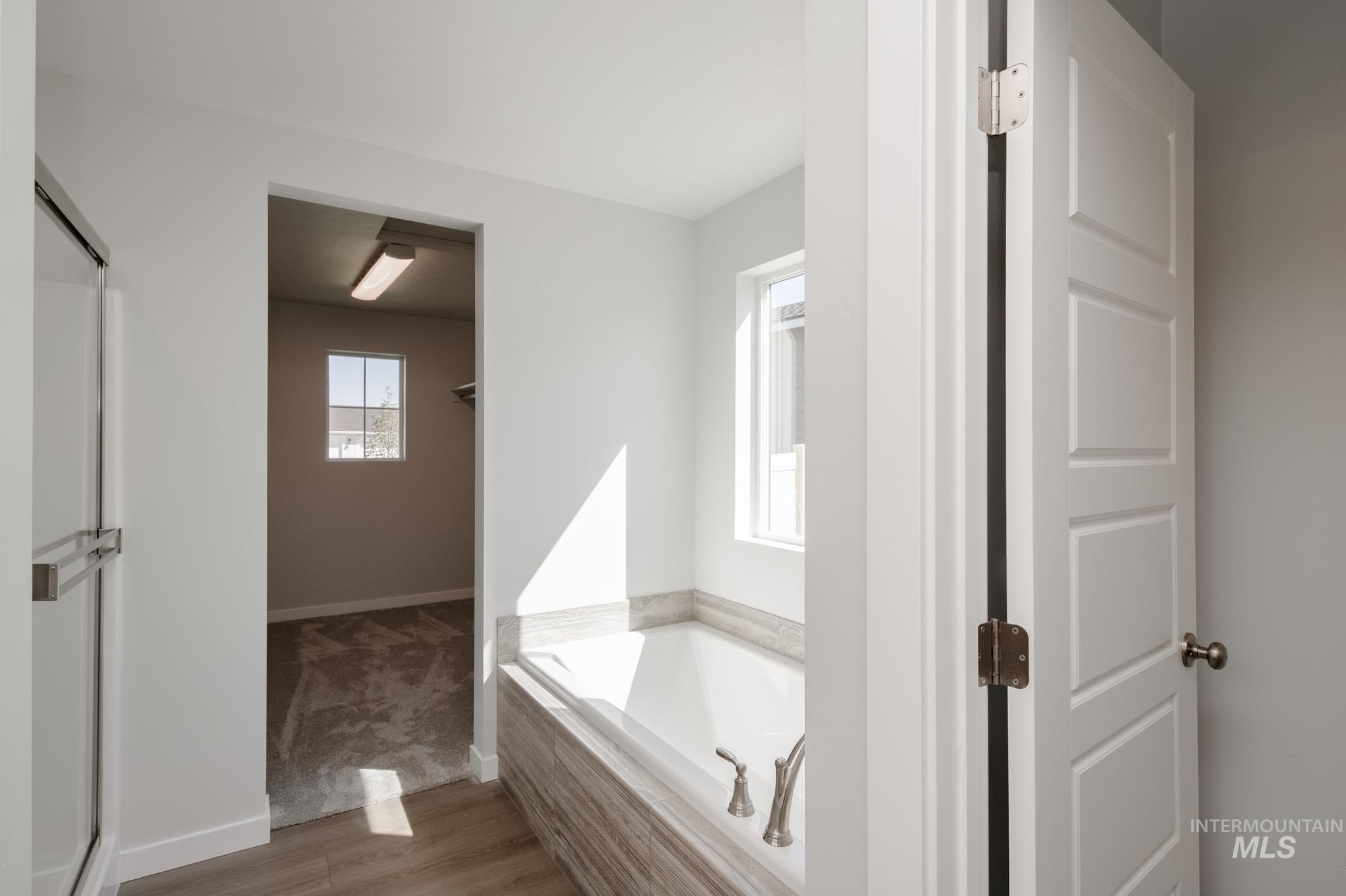 Bathroom with wood finished floors, a garden tub, and a shower stall