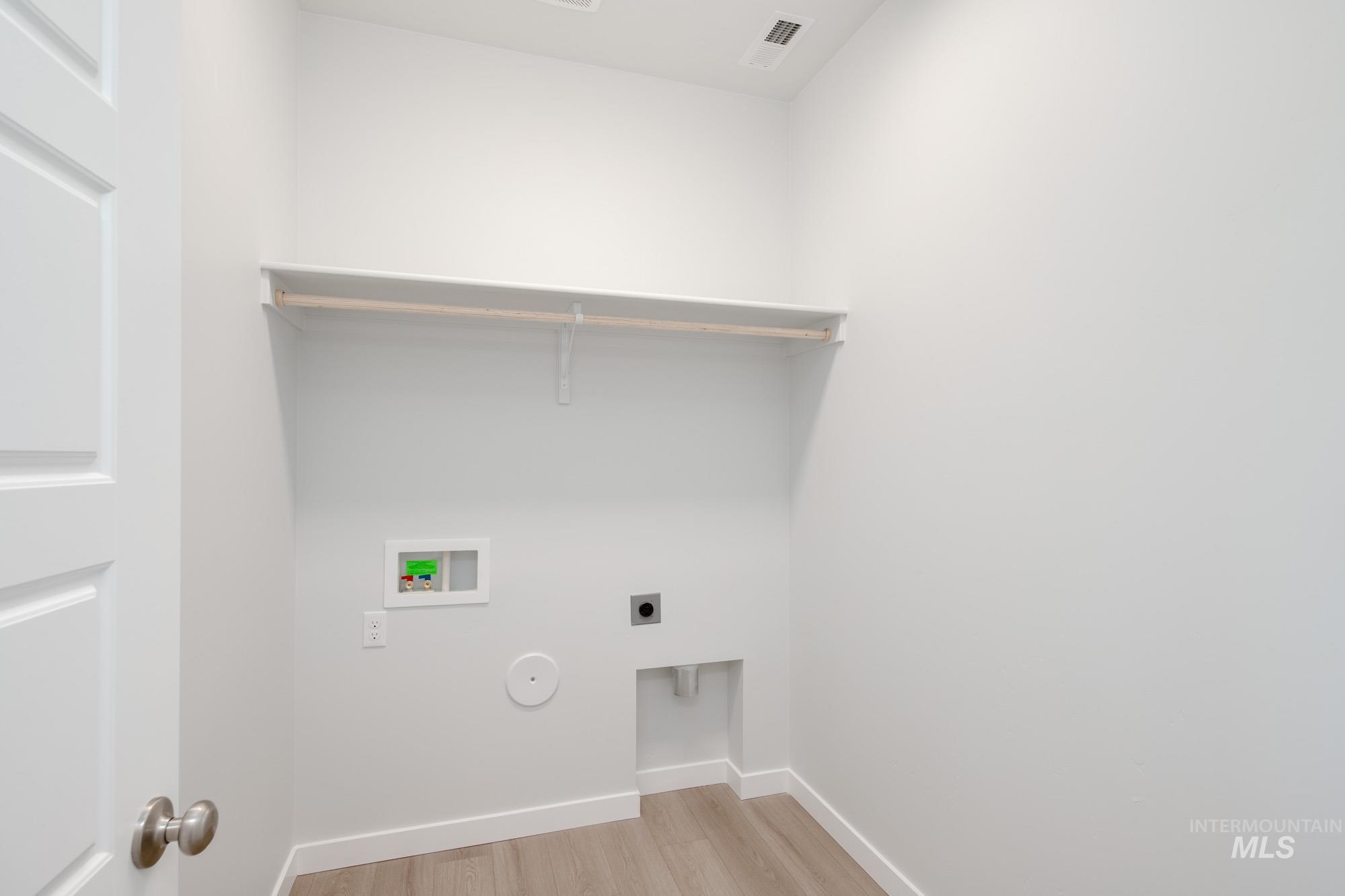 Washroom with light wood-style flooring, hookup for a washing machine, and hookup for an electric dryer