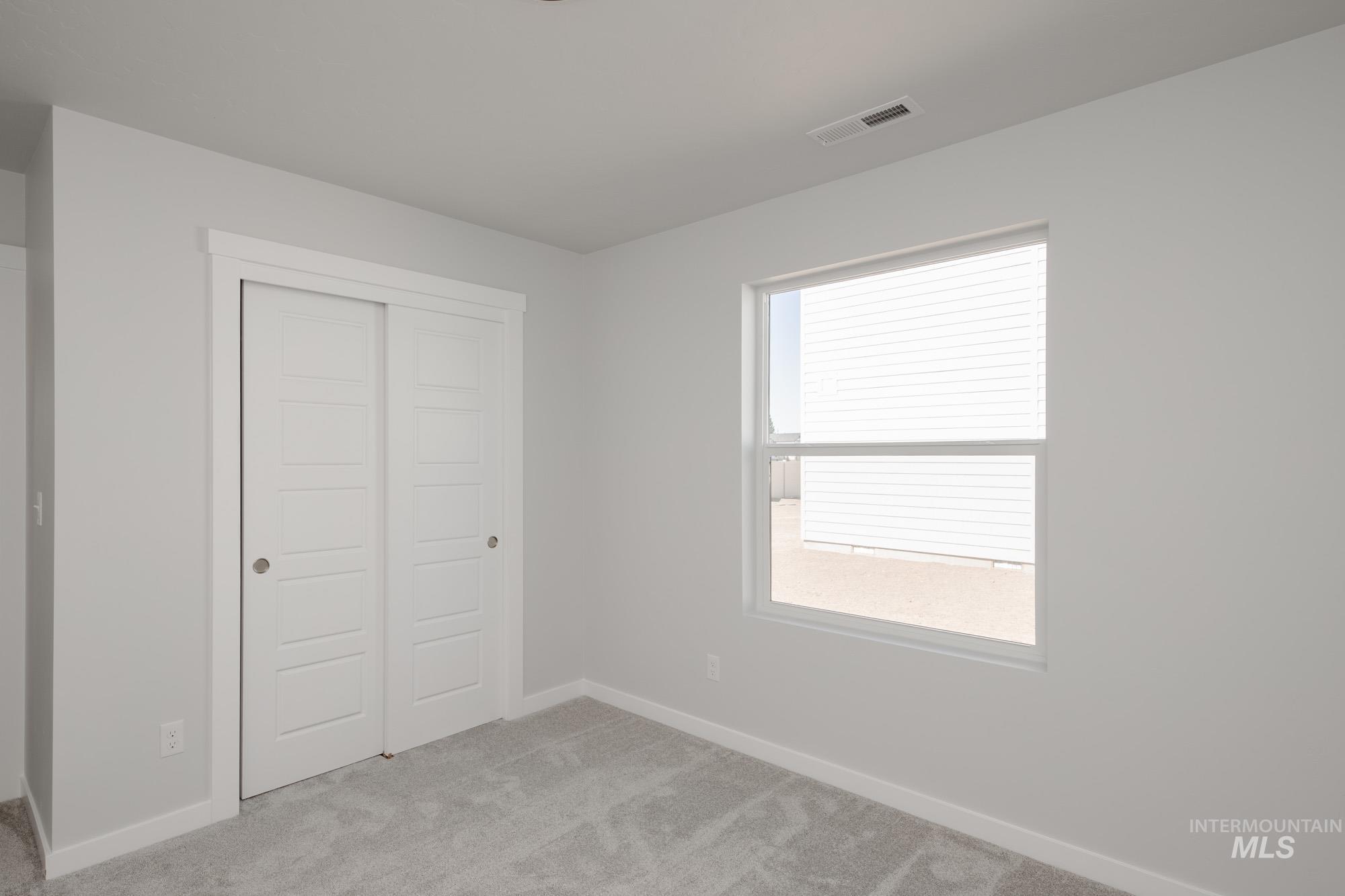 Unfurnished bedroom featuring light carpet and a closet