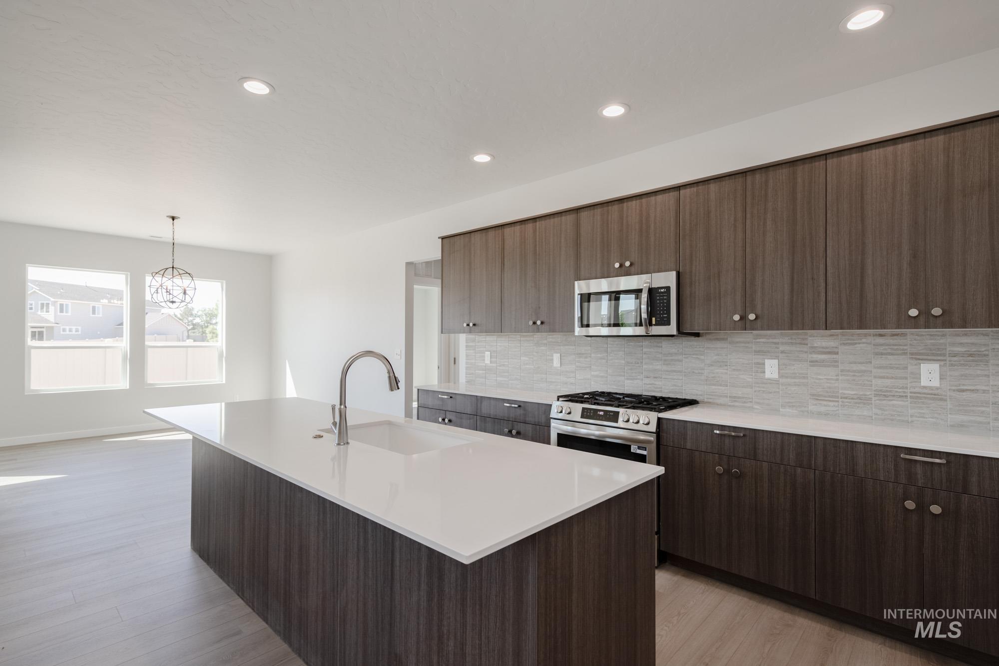 Kitchen with a kitchen island with sink, tasteful backsplash, recessed lighting, stainless steel appliances, and modern cabinets