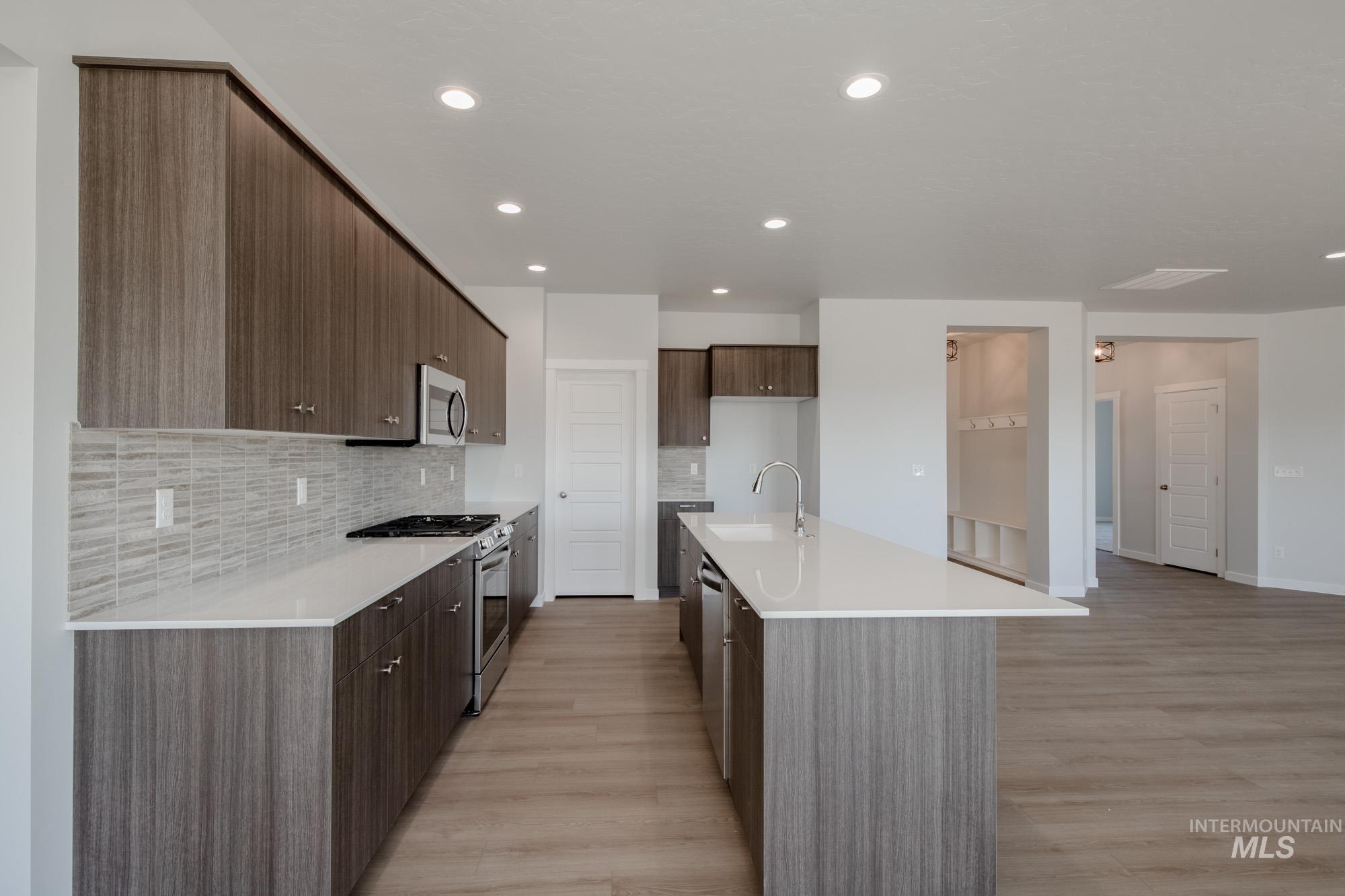 Kitchen with appliances with stainless steel finishes, modern cabinets, a kitchen island with sink, tasteful backsplash, and recessed lighting