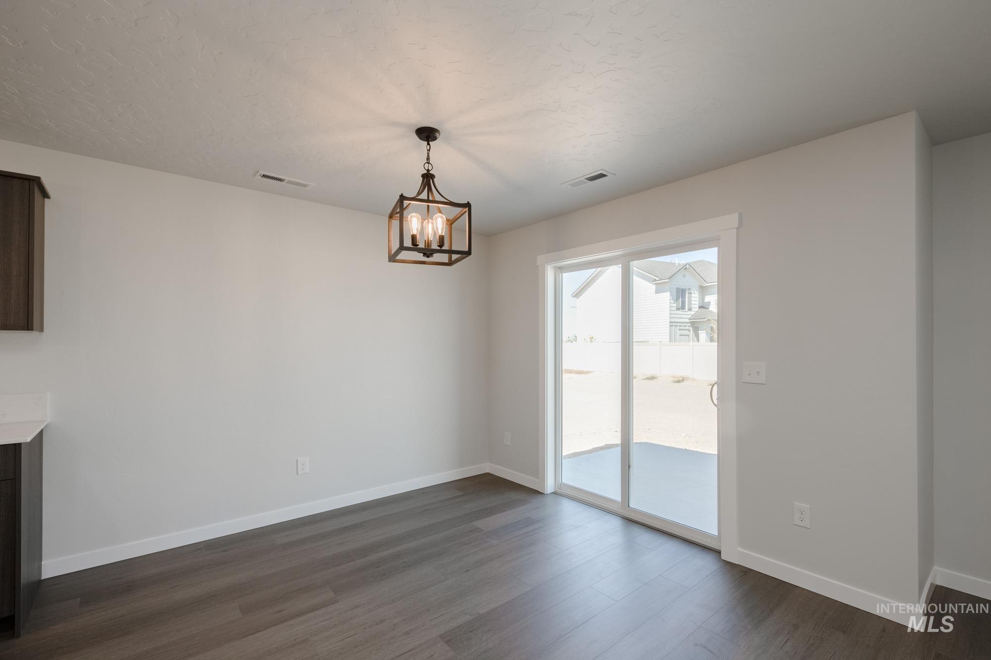 Unfurnished dining area featuring dark wood-type flooring and a chandelier