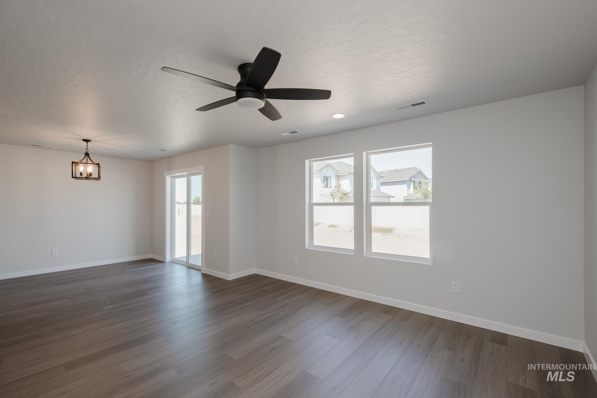 Empty room with dark wood-type flooring, a textured ceiling, and ceiling fan