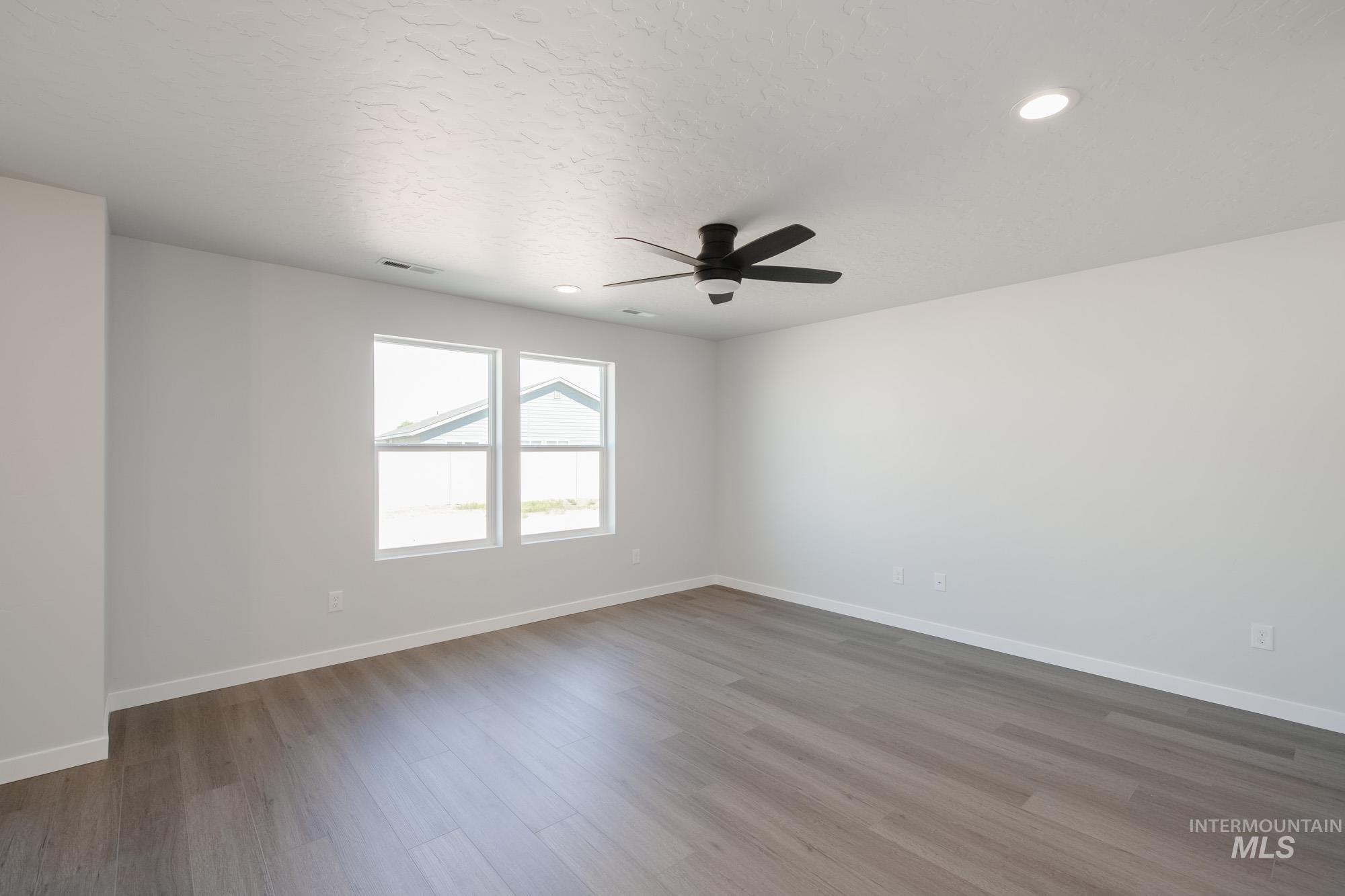 Empty room with light wood finished floors, recessed lighting, ceiling fan, and a textured ceiling