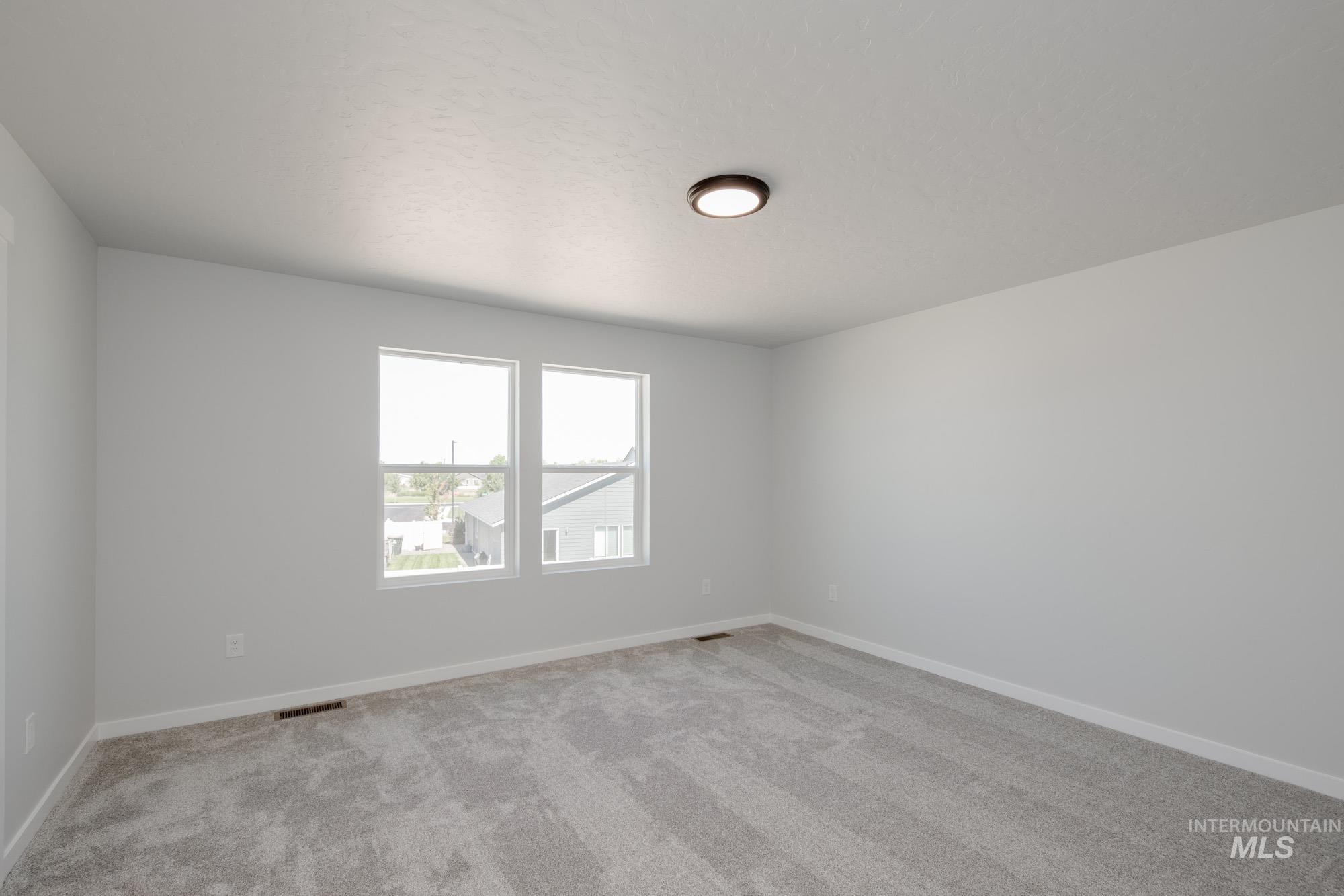 Empty room featuring light colored carpet and baseboards