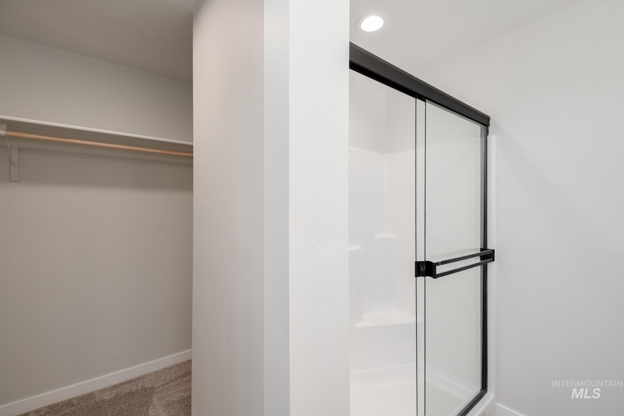 Bathroom with a walk in closet and a stall shower
