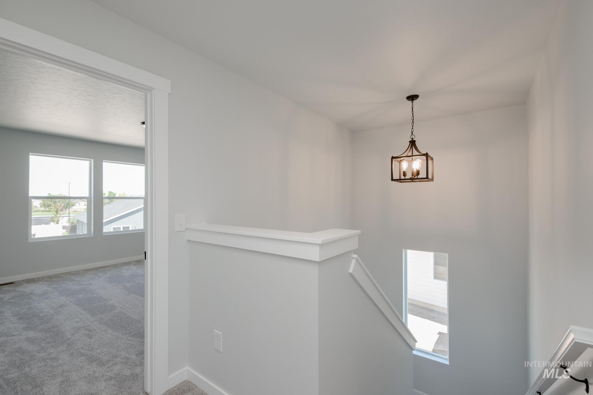 Stairs with carpet floors and a chandelier