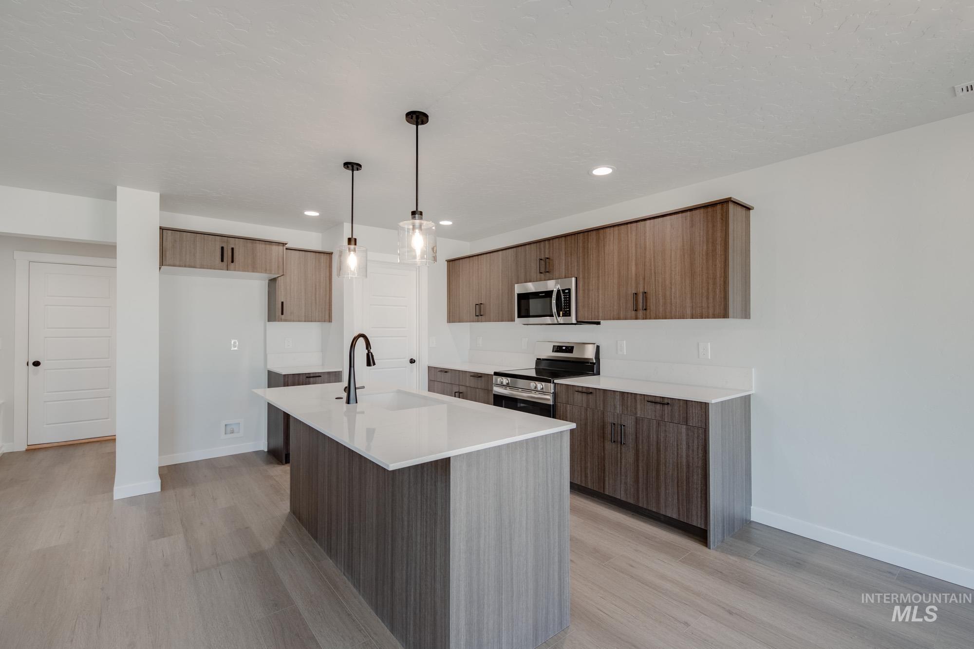 Kitchen featuring appliances with stainless steel finishes, decorative light fixtures, a center island with sink, modern cabinets, and recessed lighting