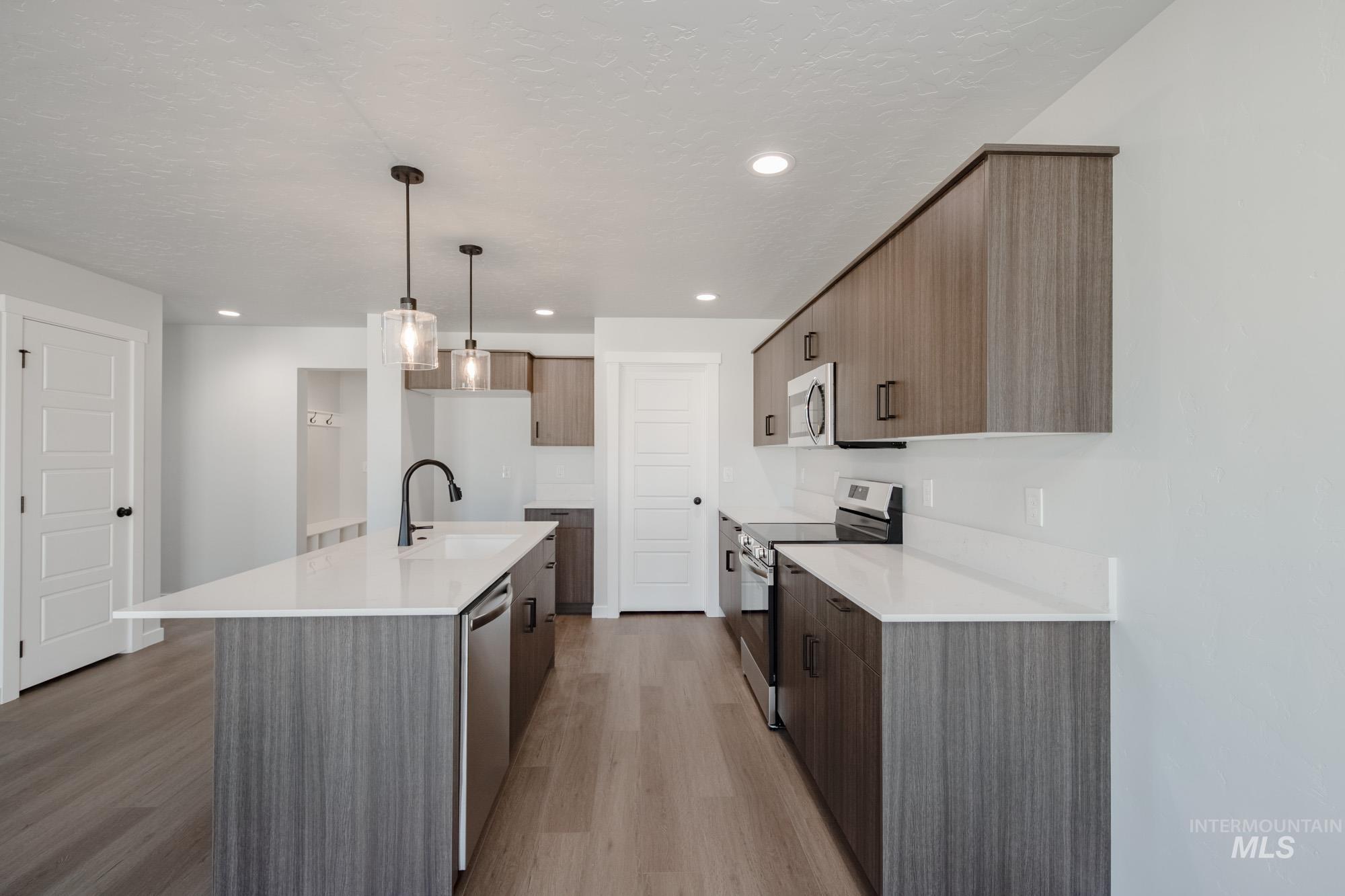 Kitchen with stainless steel appliances, modern cabinets, an island with sink, light wood-style flooring, and recessed lighting
