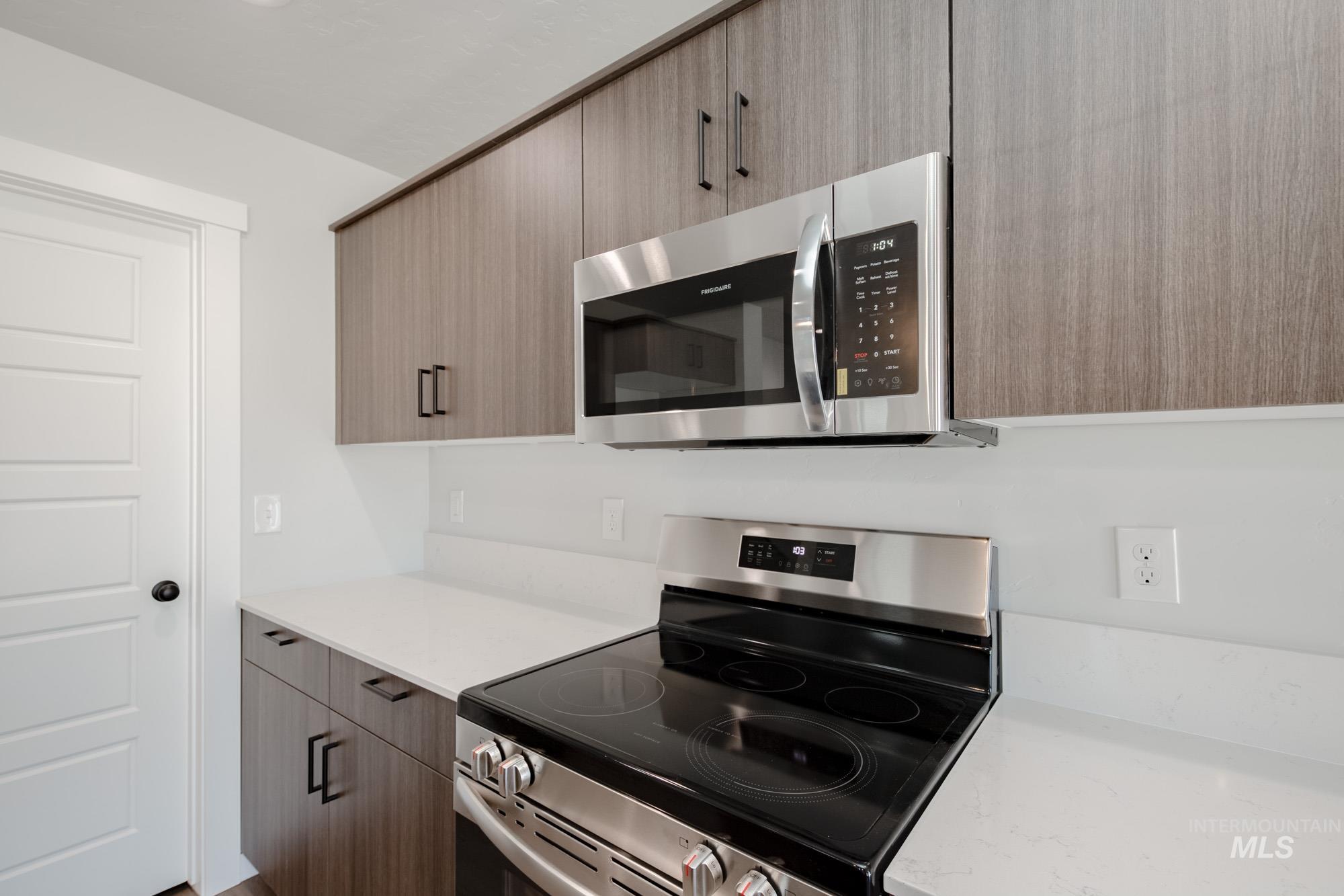 Kitchen featuring appliances with stainless steel finishes, light stone counters, and modern cabinets