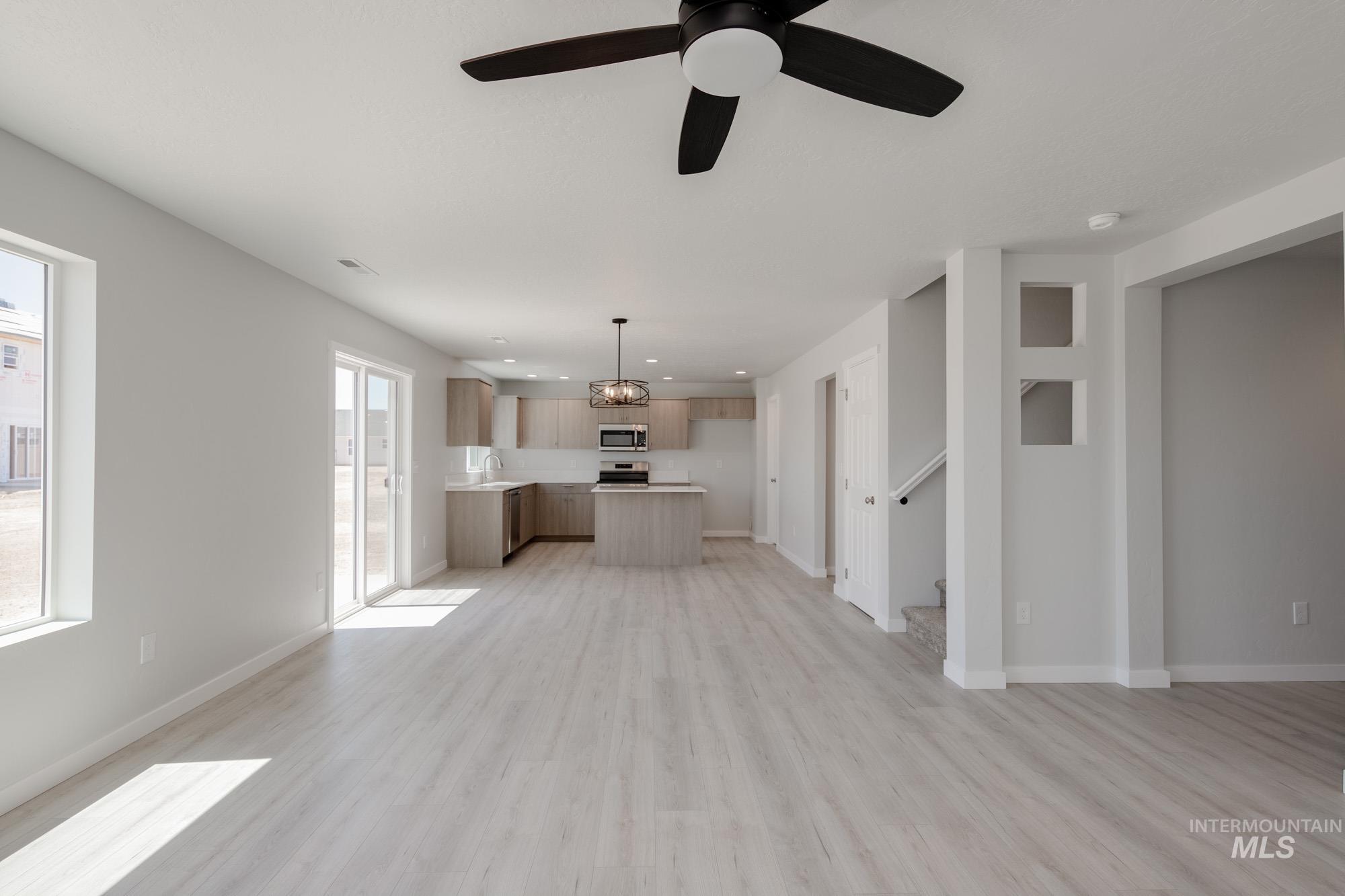 Unfurnished living room with light wood-style floors, ceiling fan, stairway, and recessed lighting