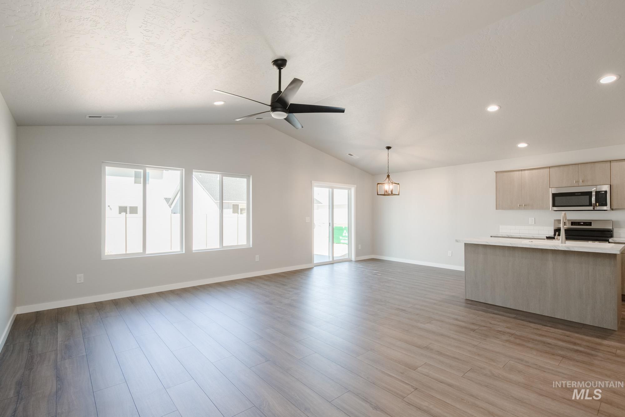 Unfurnished living room featuring light wood-style floors, vaulted ceiling, ceiling fan, recessed lighting, and a textured ceiling