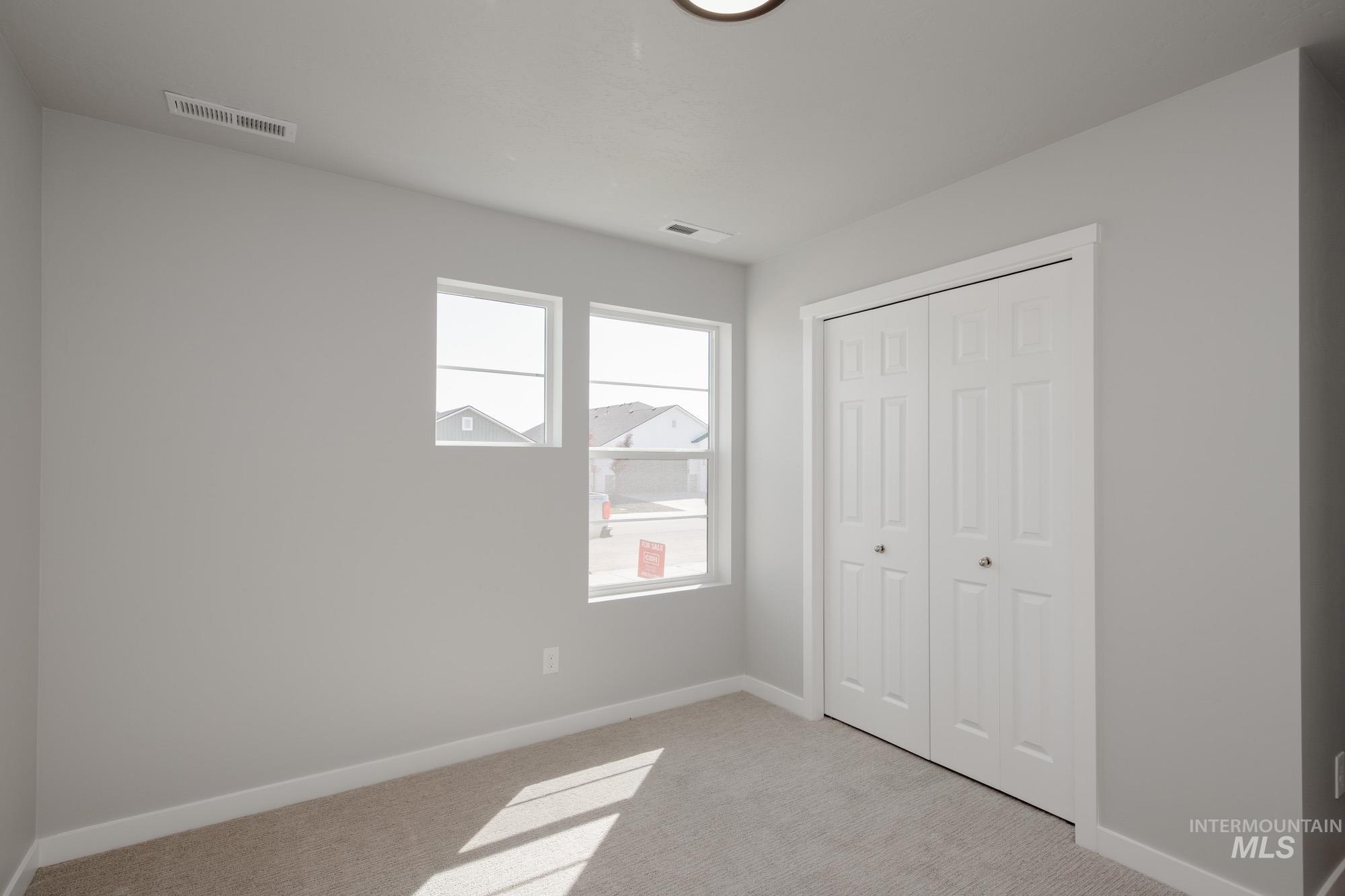 Unfurnished bedroom with light carpet and a closet