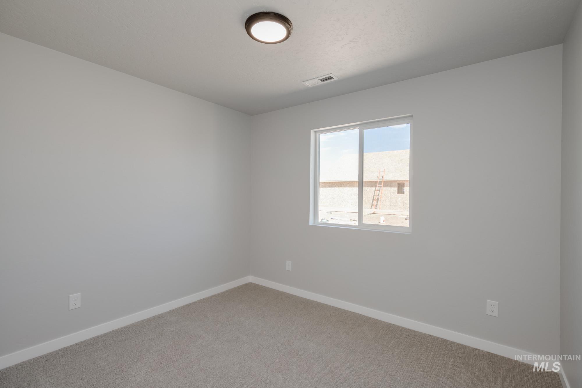 Carpeted spare room featuring baseboards
