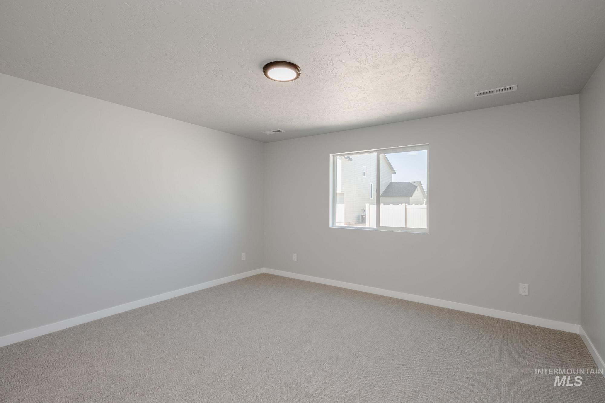 Empty room featuring light carpet and a textured ceiling